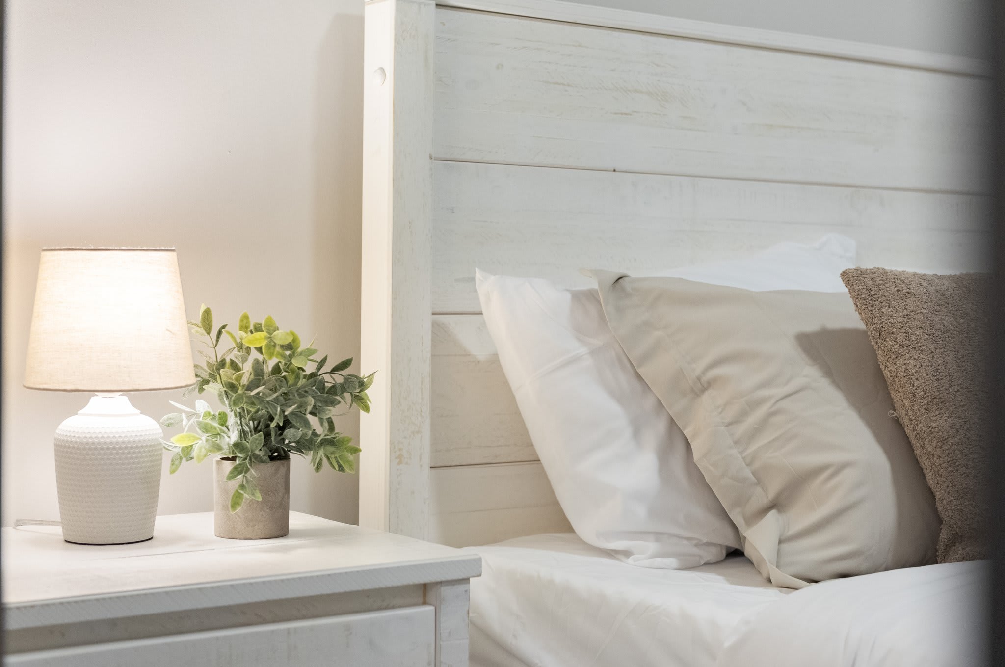 A little vignette of comfort: a soft lamp glow, simple décor, and plush bedding. It’s the small touches that make it feel like home.