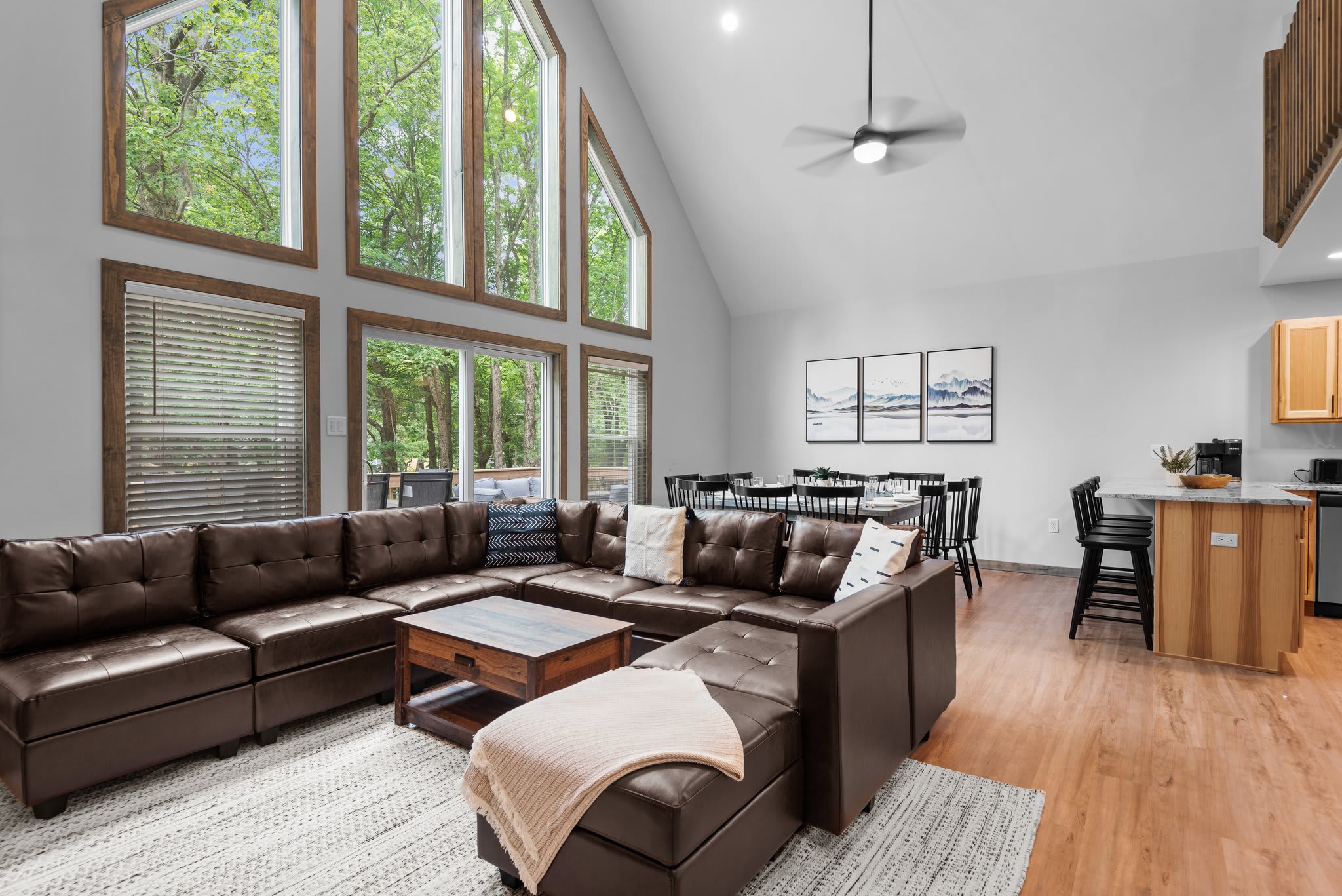 Flooded with natural light from towering windows, this open-concept living space is the heart of the home, perfect for cozy nights in or morning coffee with a view of the trees.