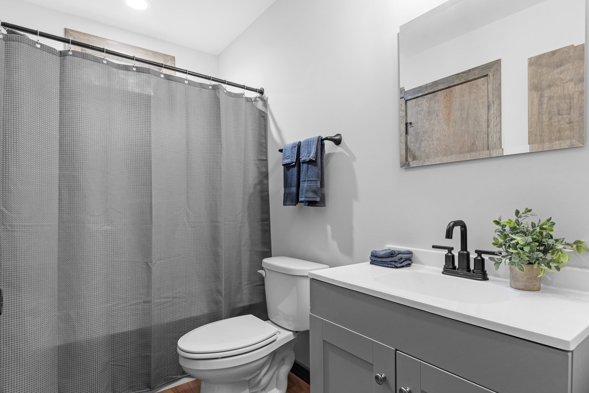 Clean and modern with a full tub and sleek matte black finishes. Bright lighting and natural tones keep it fresh and simple.