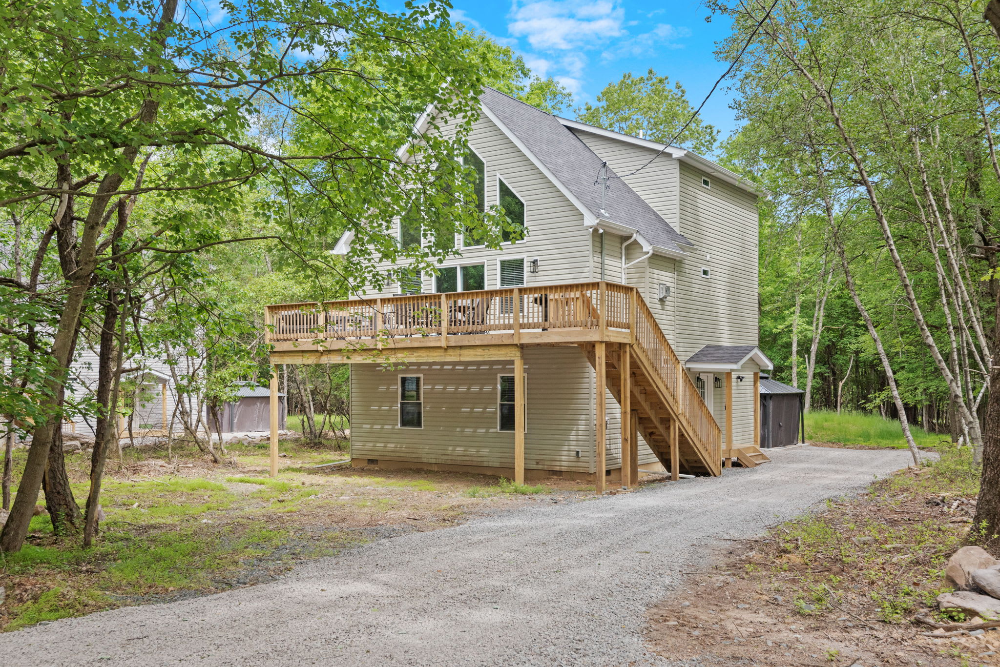 Angled Exterior Front View
A beautiful shot of the front showing off the elevated deck and private gravel drive surrounded by nature.