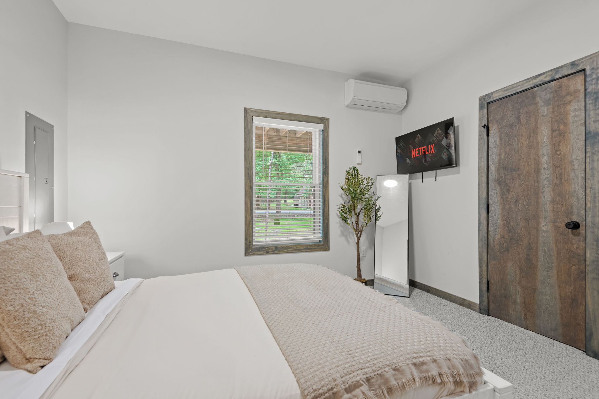 Spacious and light-filled, this room includes a mounted TV and easy access to the hallway for added convenience.