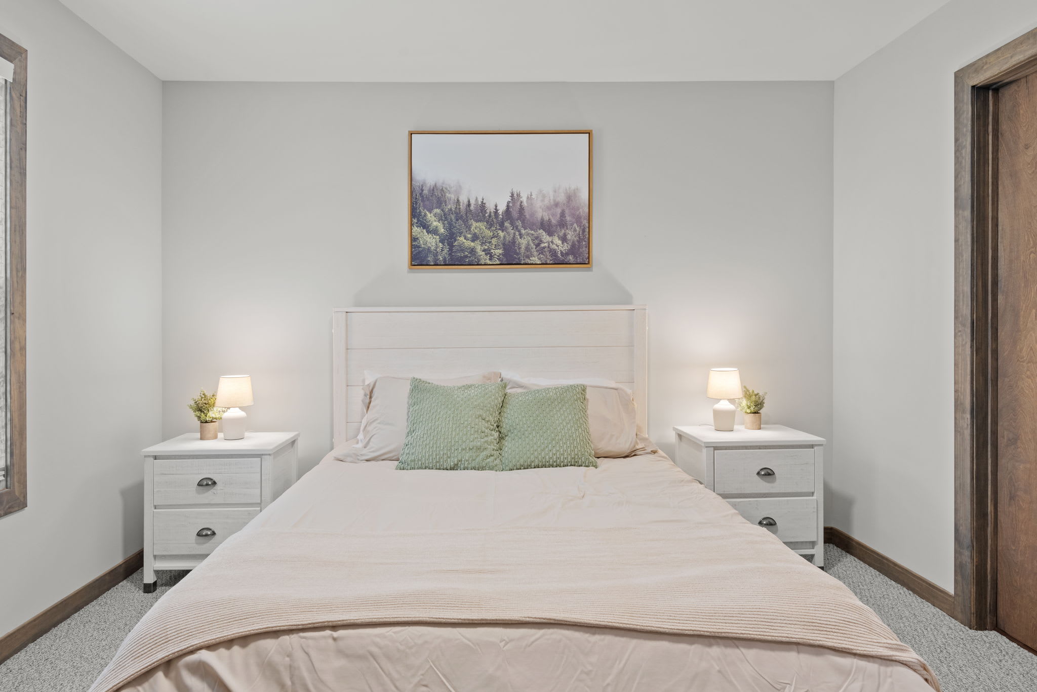 A soft and simple queen bedroom with warm tones, natural light, and peaceful mountain artwork to complete the calm vibe.