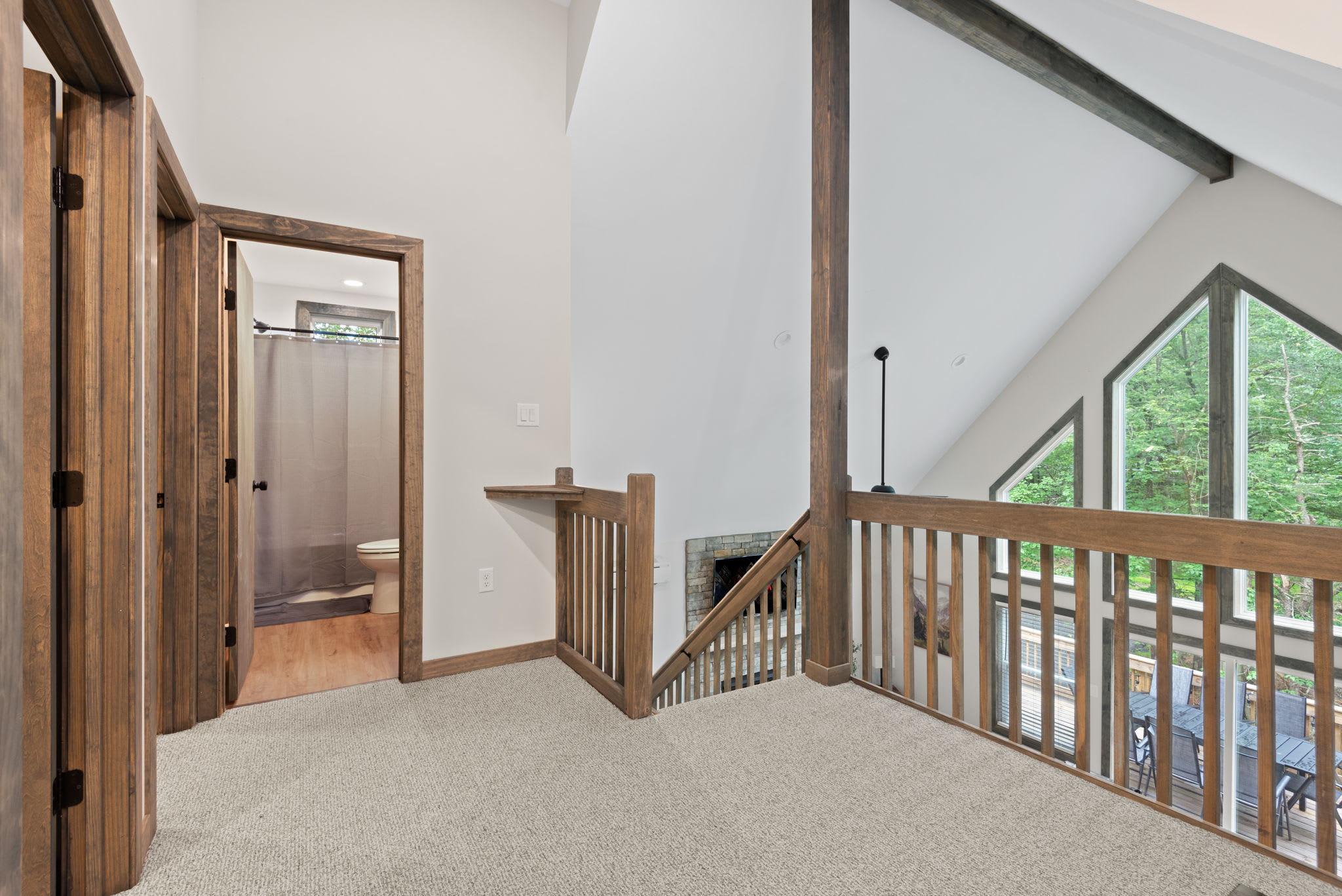 A bright and open loft area overlooking the main level. Exposed beams and large windows give it a cozy, elevated charm.
