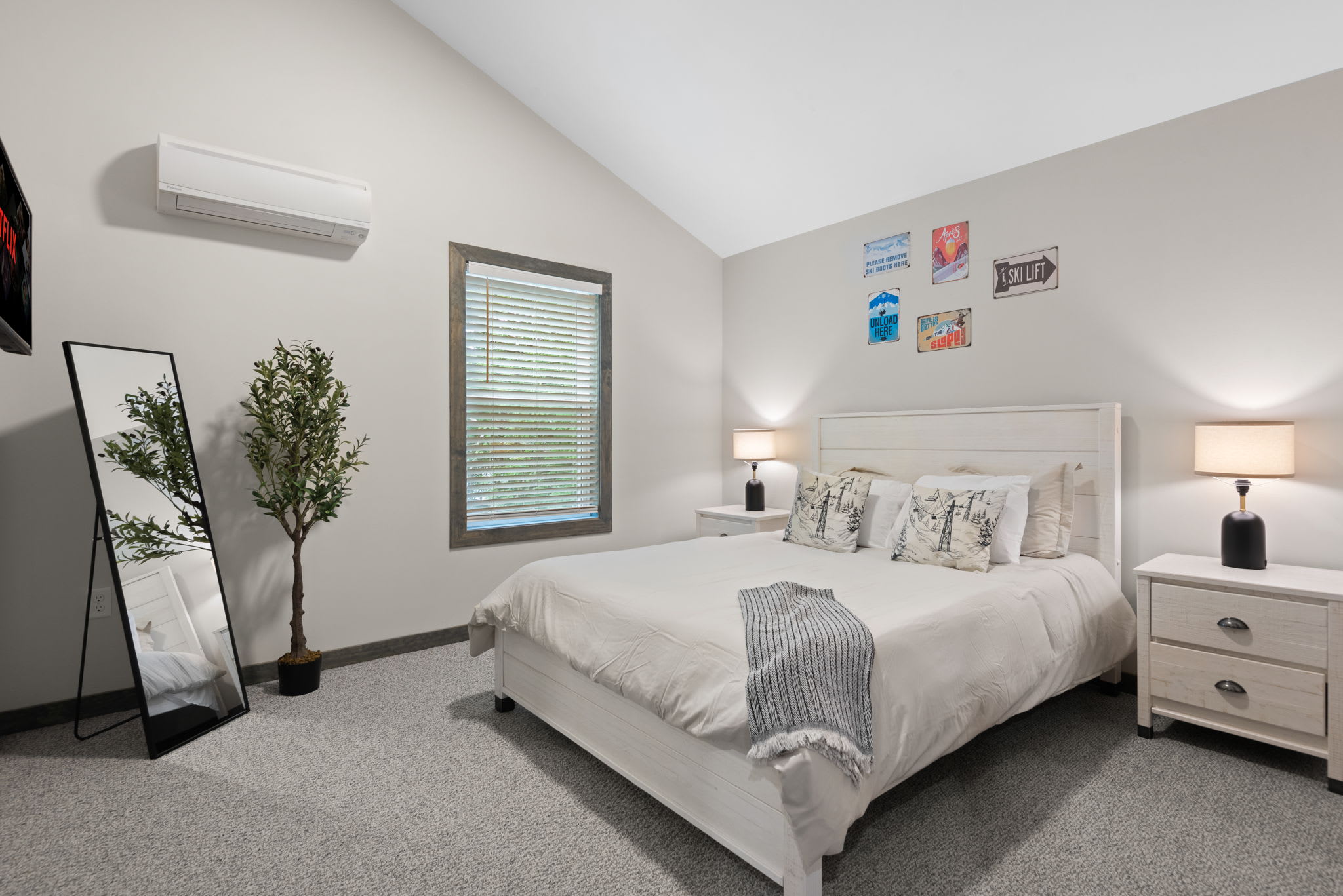 Spacious and bright with vaulted ceilings, this top-floor room includes a full-length mirror, queen bed, and soft neutral decor.