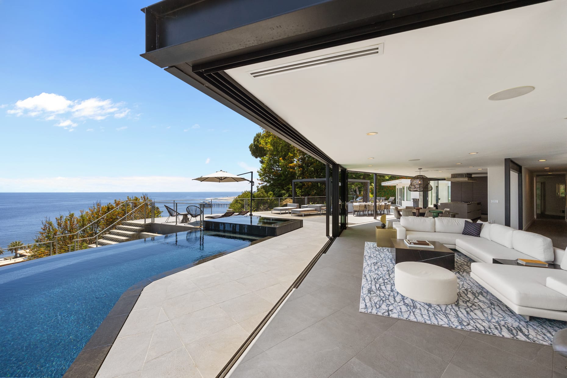 The living room boasts floor-to-ceiling glass doors with breathtaking ocean views.