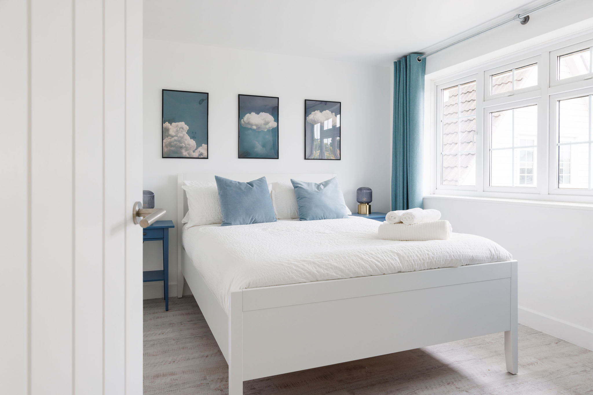 Serene bedroom with cloud-themed wall art and soft blue accents for a dreamy atmosphere