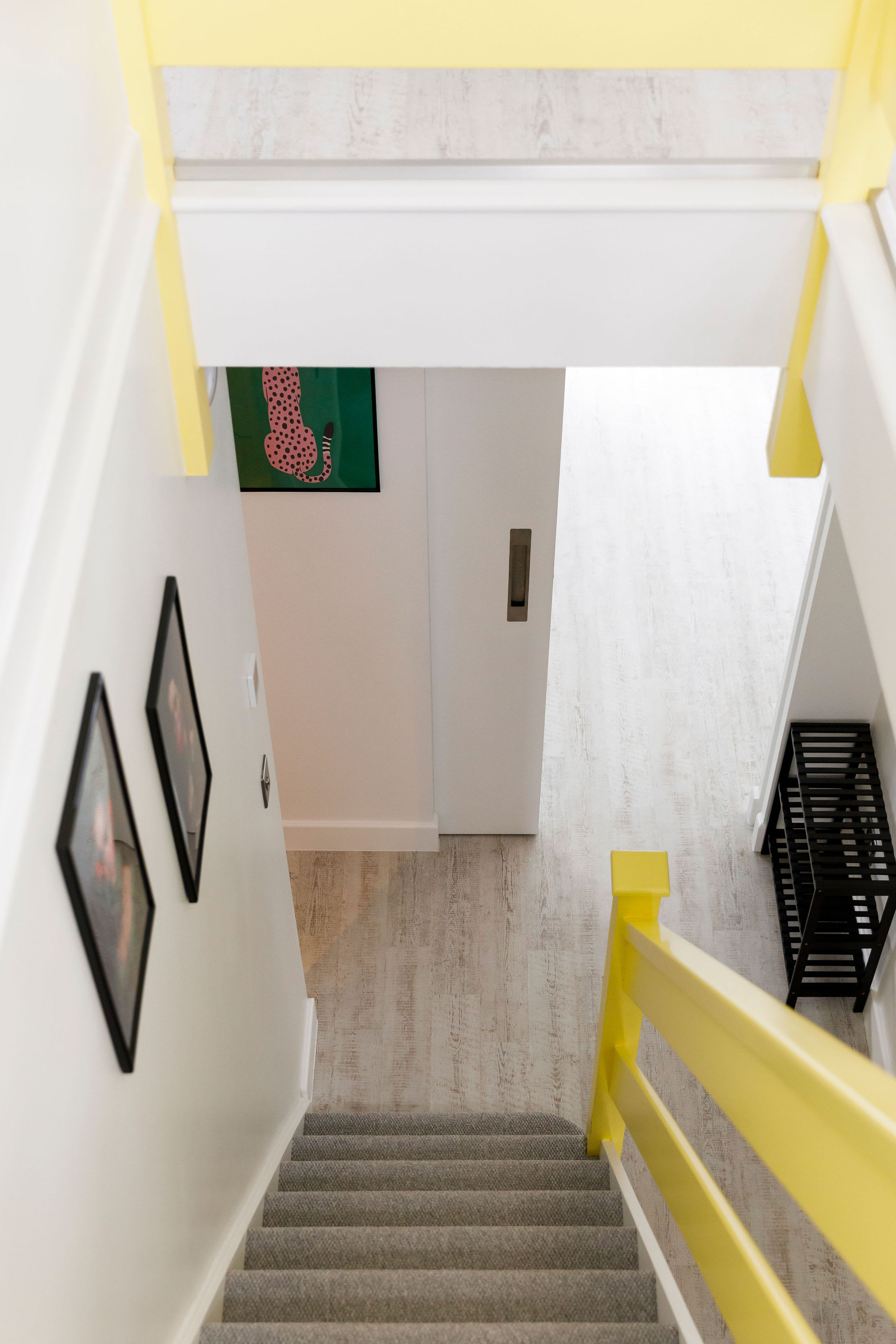 Bright and inviting staircase area with a pop of yellow on the railing