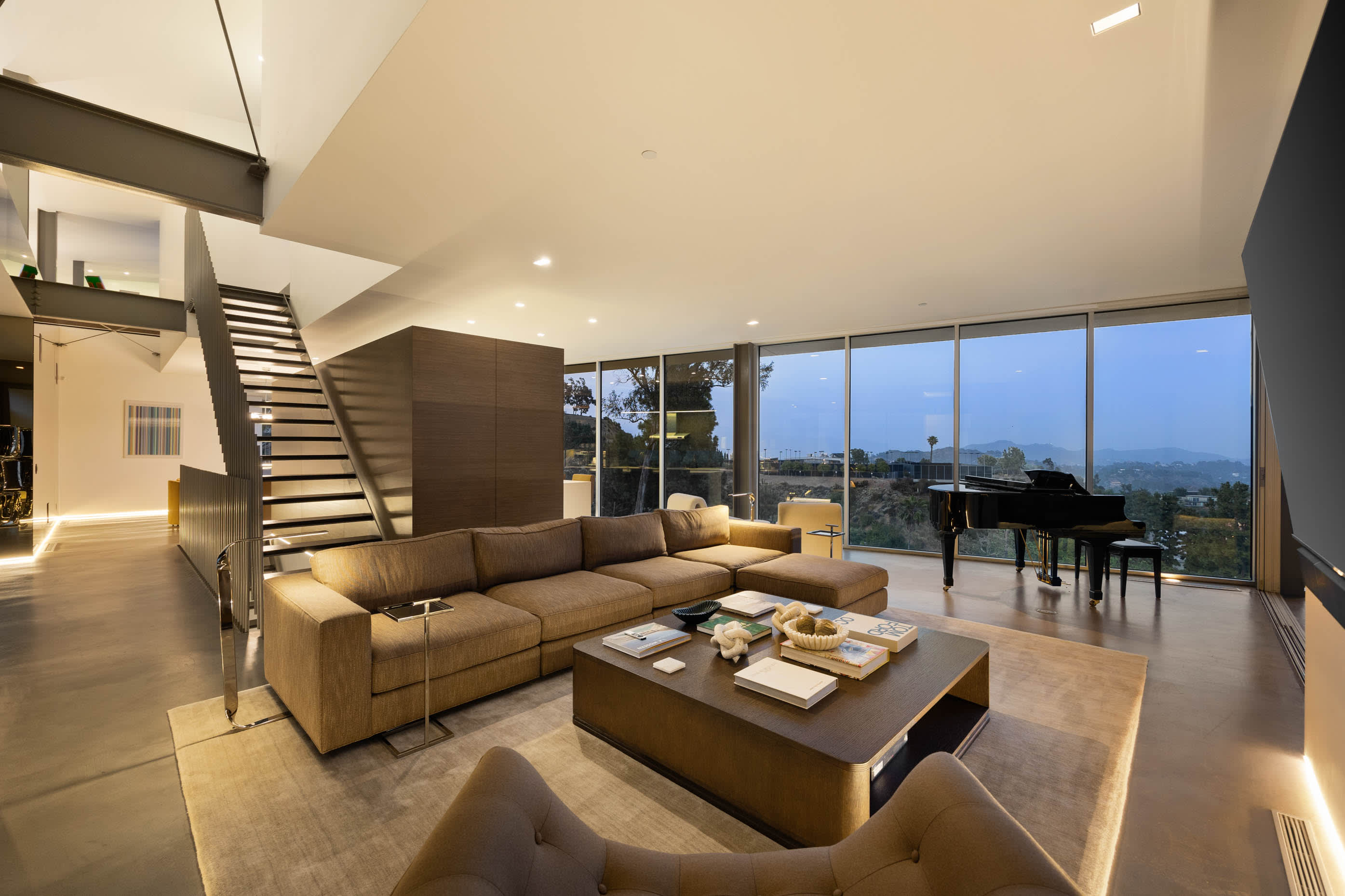 Luxurious living room with glass walls offering breathtaking night views of the city skyline.