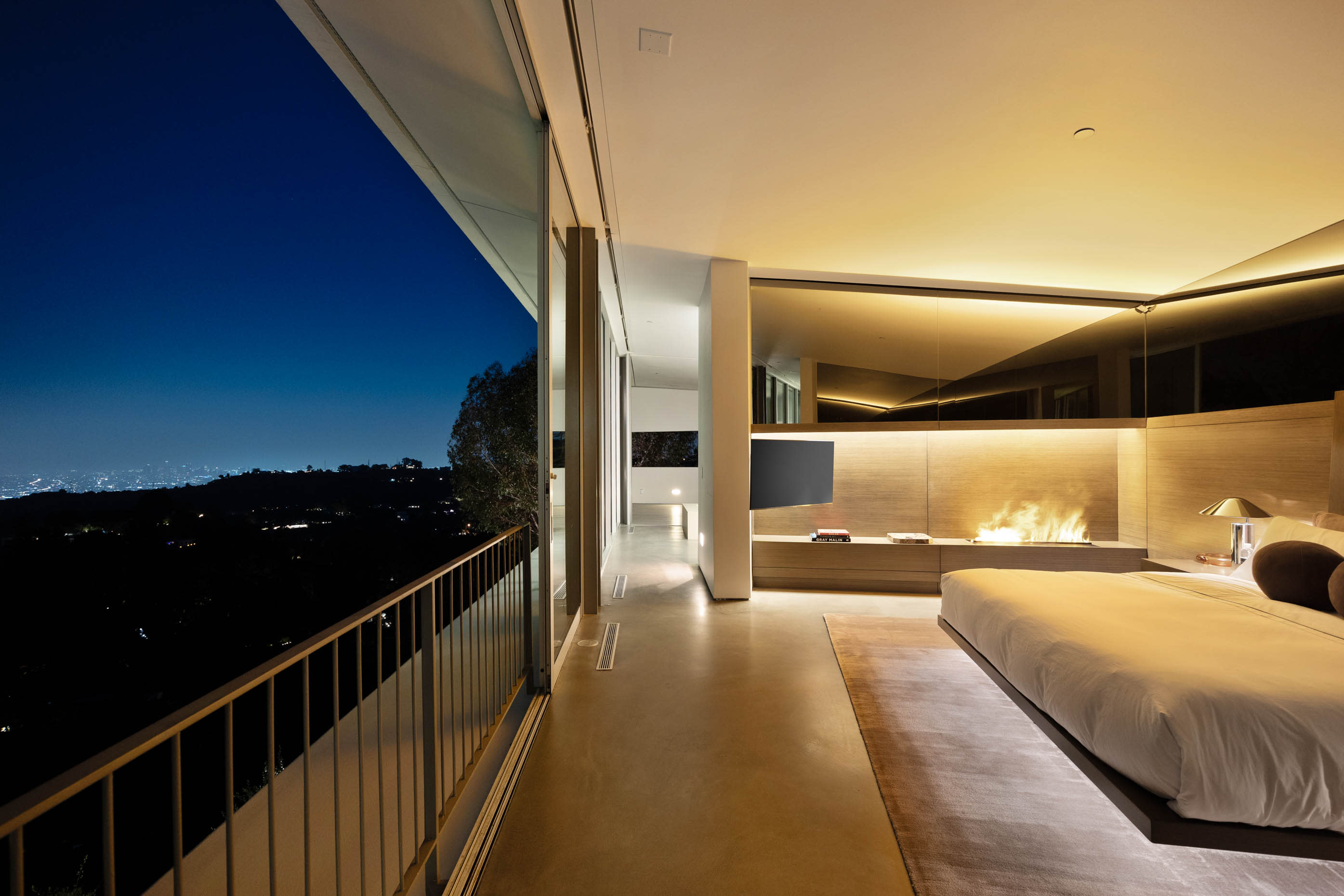 Sumptuous bedroom with a wall of glass sliding doors, revealing stunning city lights.