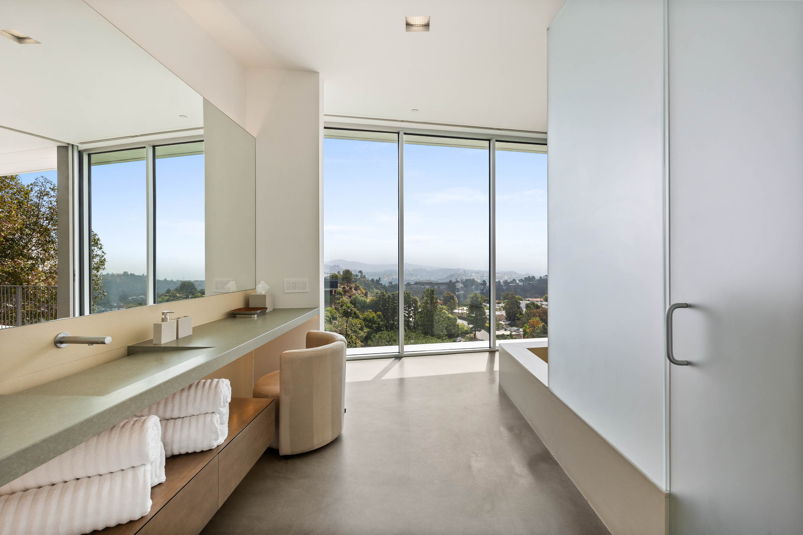 Elegant dressing area with a vanity, positioned next to expansive windows offering serene views.
