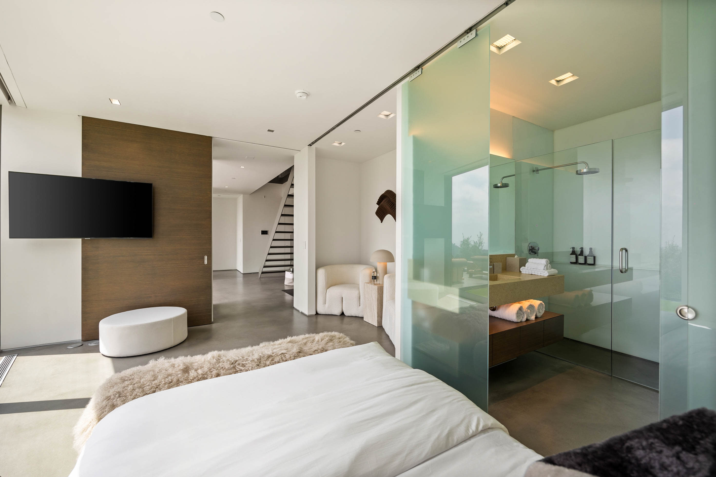 Private ensuite featuring a glass-encased design with a luxurious rain shower and refined simplicity.