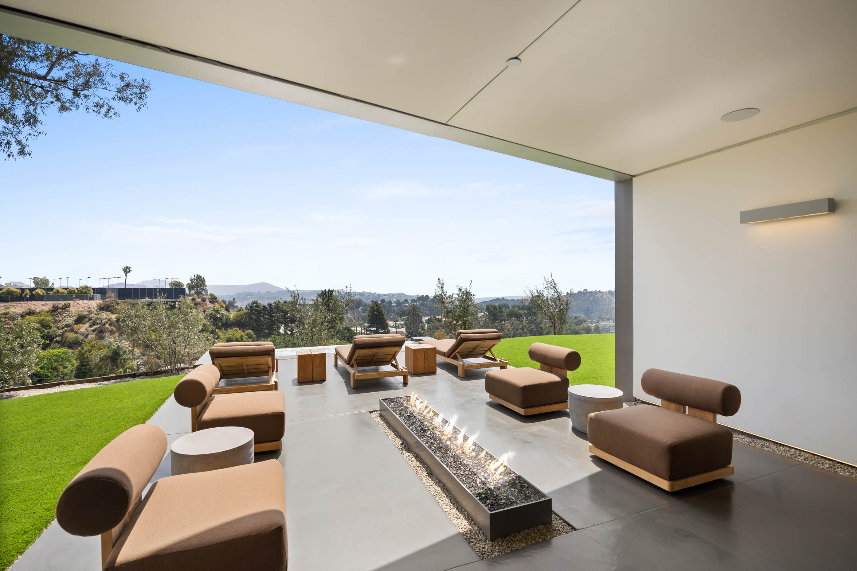 Spacious outdoor seating area surrounding a sleek linear fireplace.
