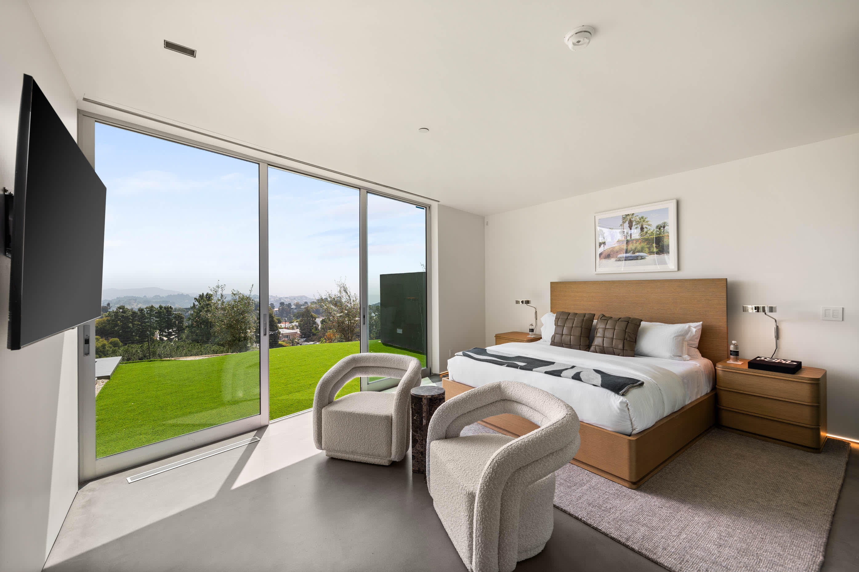 Lavish bedroom with expansive glass doors that offer breathtaking views and seamless access to nature.