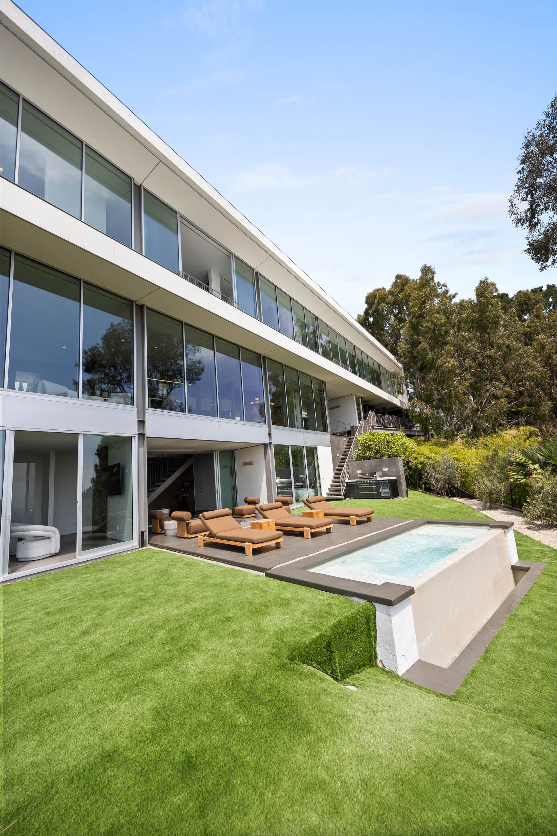 Relax in style with RH Modern furniture and sun loungers by the pool.