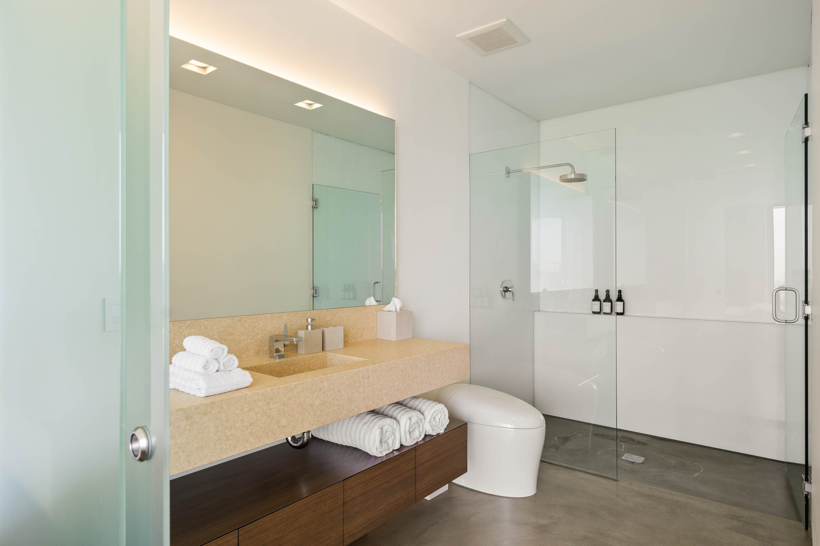 Bathroom with a spacious rain shower enclosed in sleek glass, complemented by high-end fixtures and luxurious amenities.