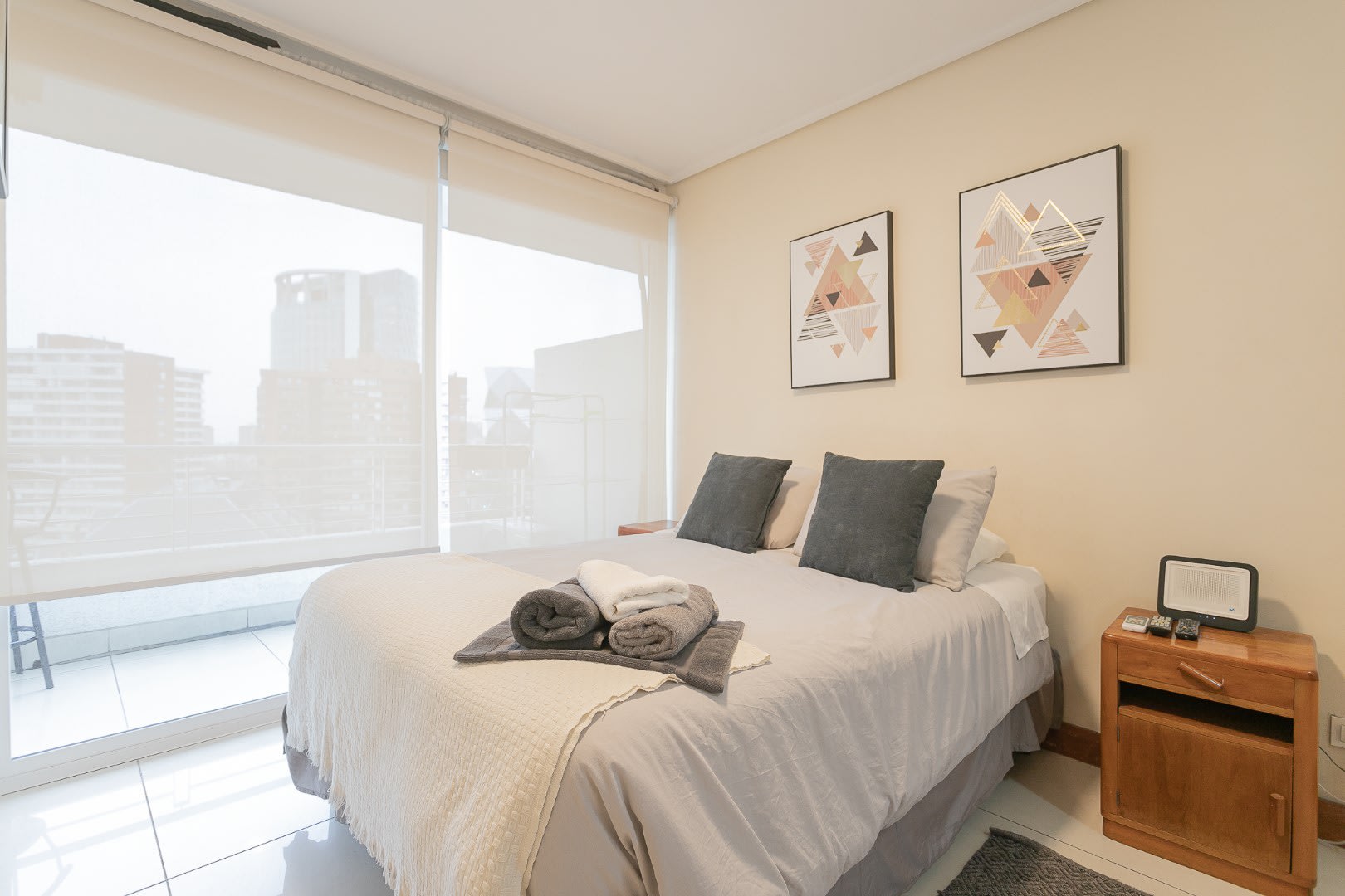 Enjoy city views from this serene bedroom, featuring modern decor and cozy bedding, perfect for relaxation.