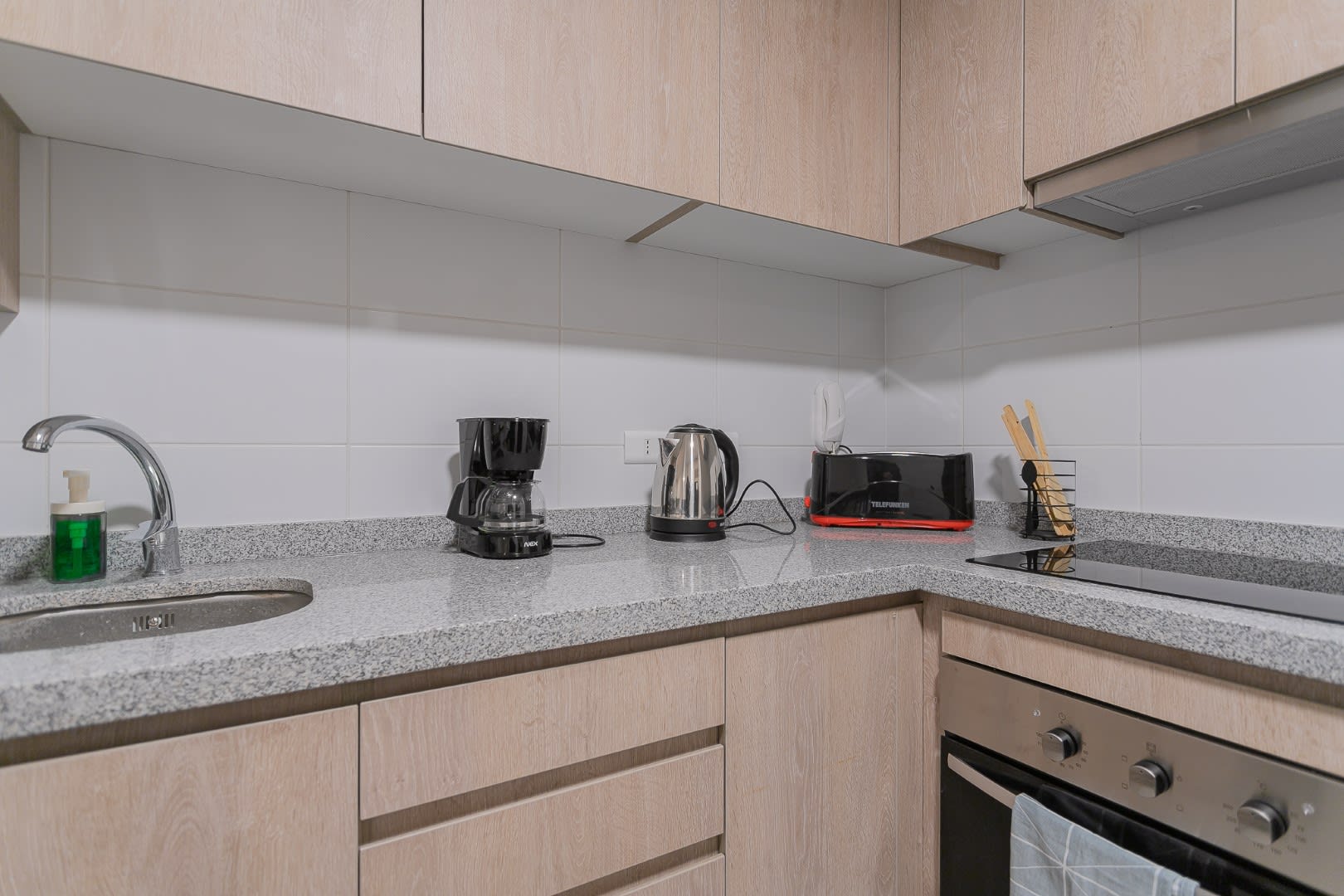Private kitchen with light wood cabinetry, granite-look counters, coffee maker, electric kettle, toaster, and a built-in oven for convenient meals.