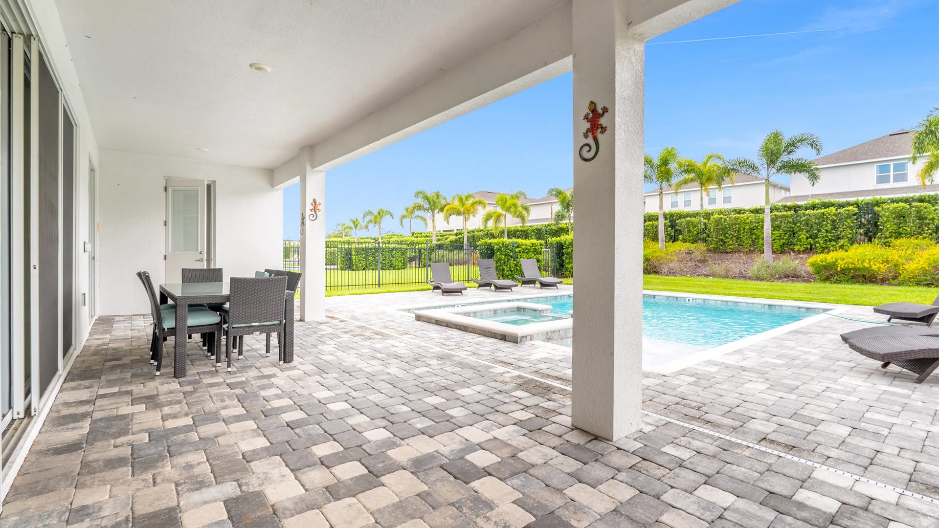 Relax in style on the spacious patio, complete with a dining area and poolside lounge chairs, surrounded by lush landscaping.