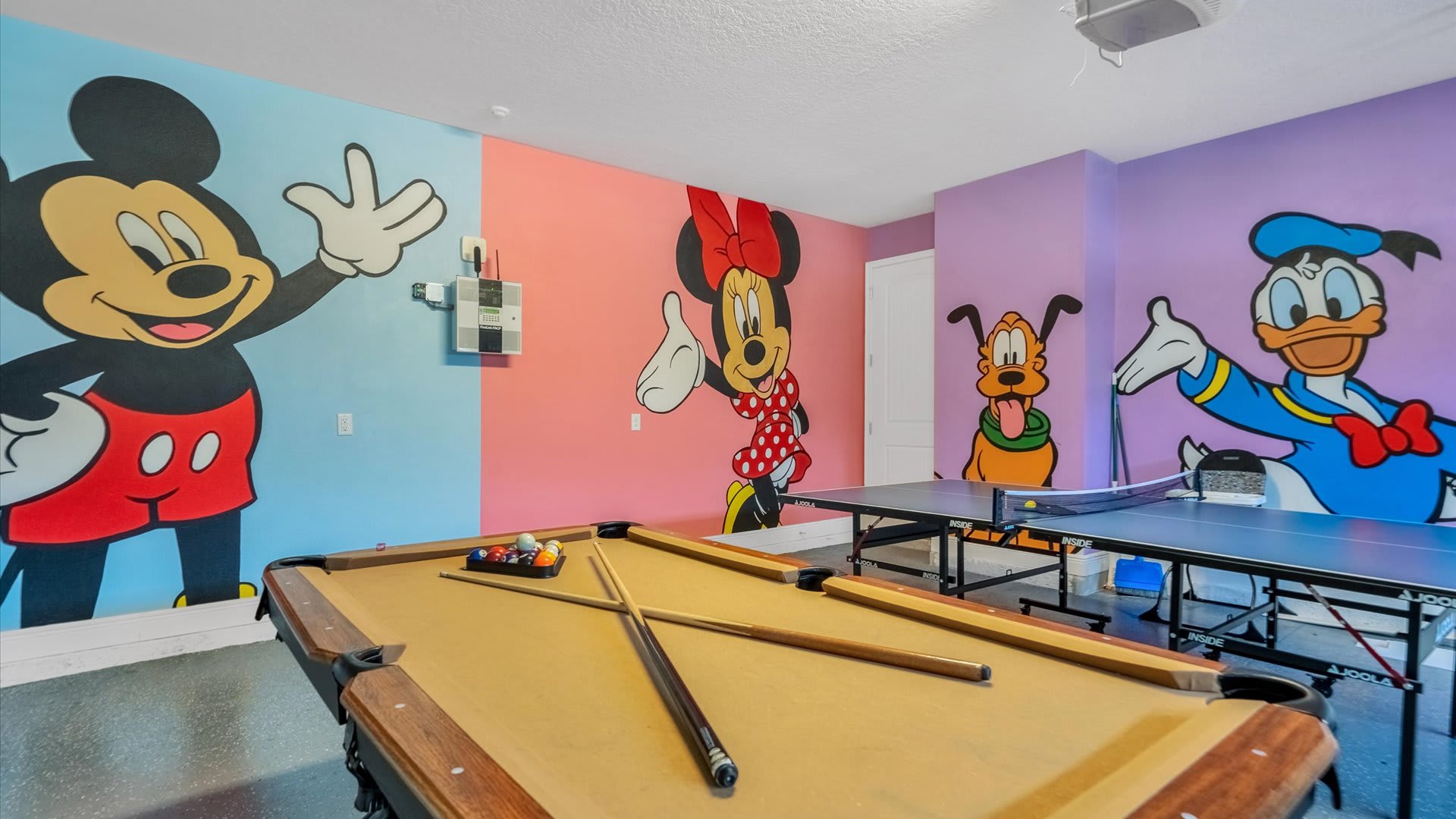 Enjoy endless fun in our vibrant game room featuring a pool table and ping pong, surrounded by playful cartoon murals!