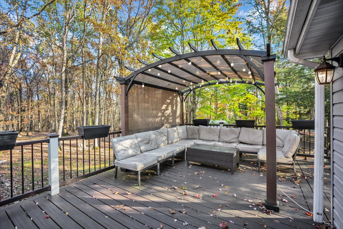 The pergola-covered deck provides a comfortable outdoor seating area, perfect for enjoying nature.