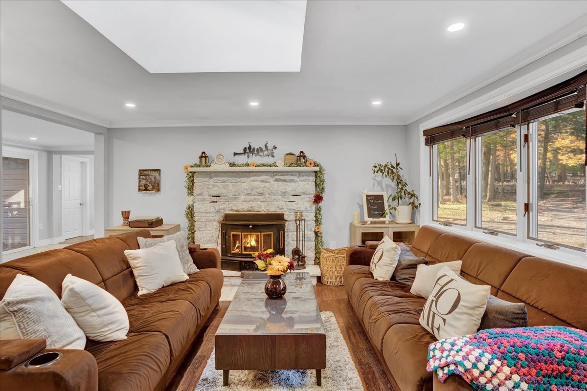Sink into plush seating and enjoy the warmth of a crackling fireplace in this inviting living space. Natural light floods through large windows, offering a front-row view of the beautiful surroundings.