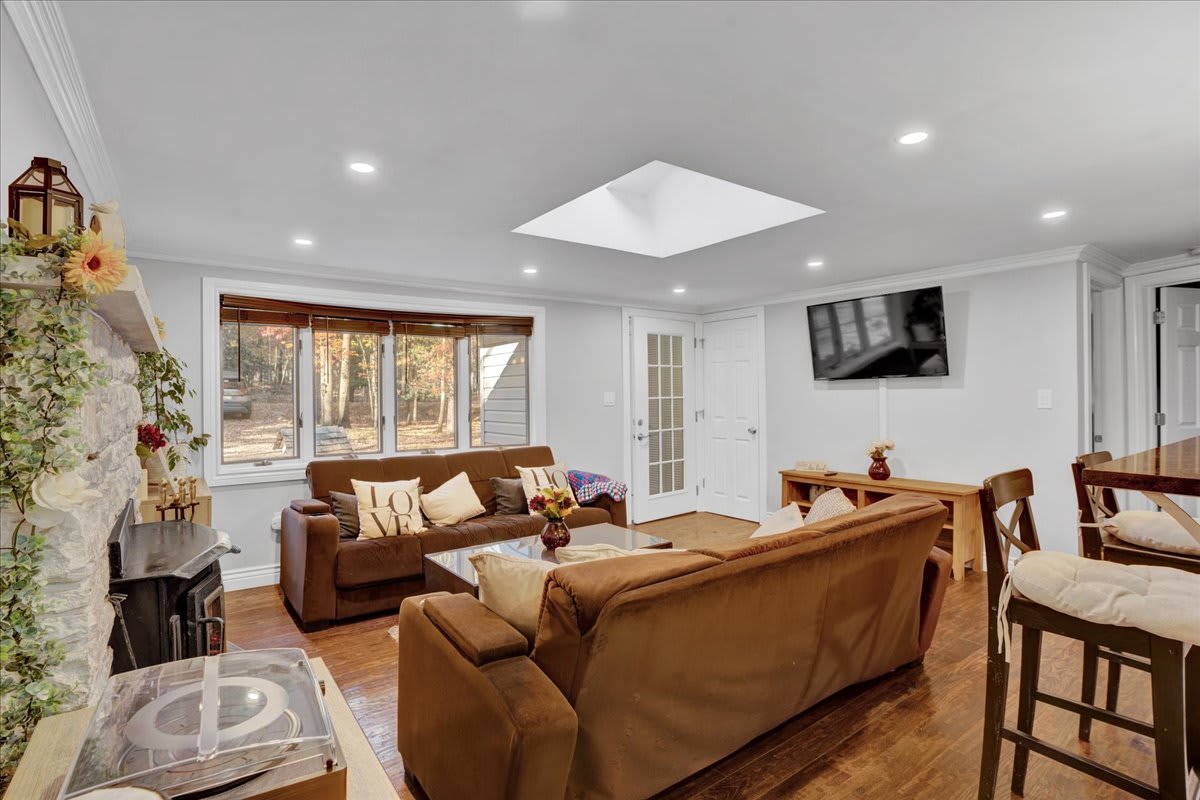 A seamless blend of comfort and style, this open-concept living space is perfect for gathering with family or friends. Plush seating, a skylight, and a TV create an ideal spot to unwind.