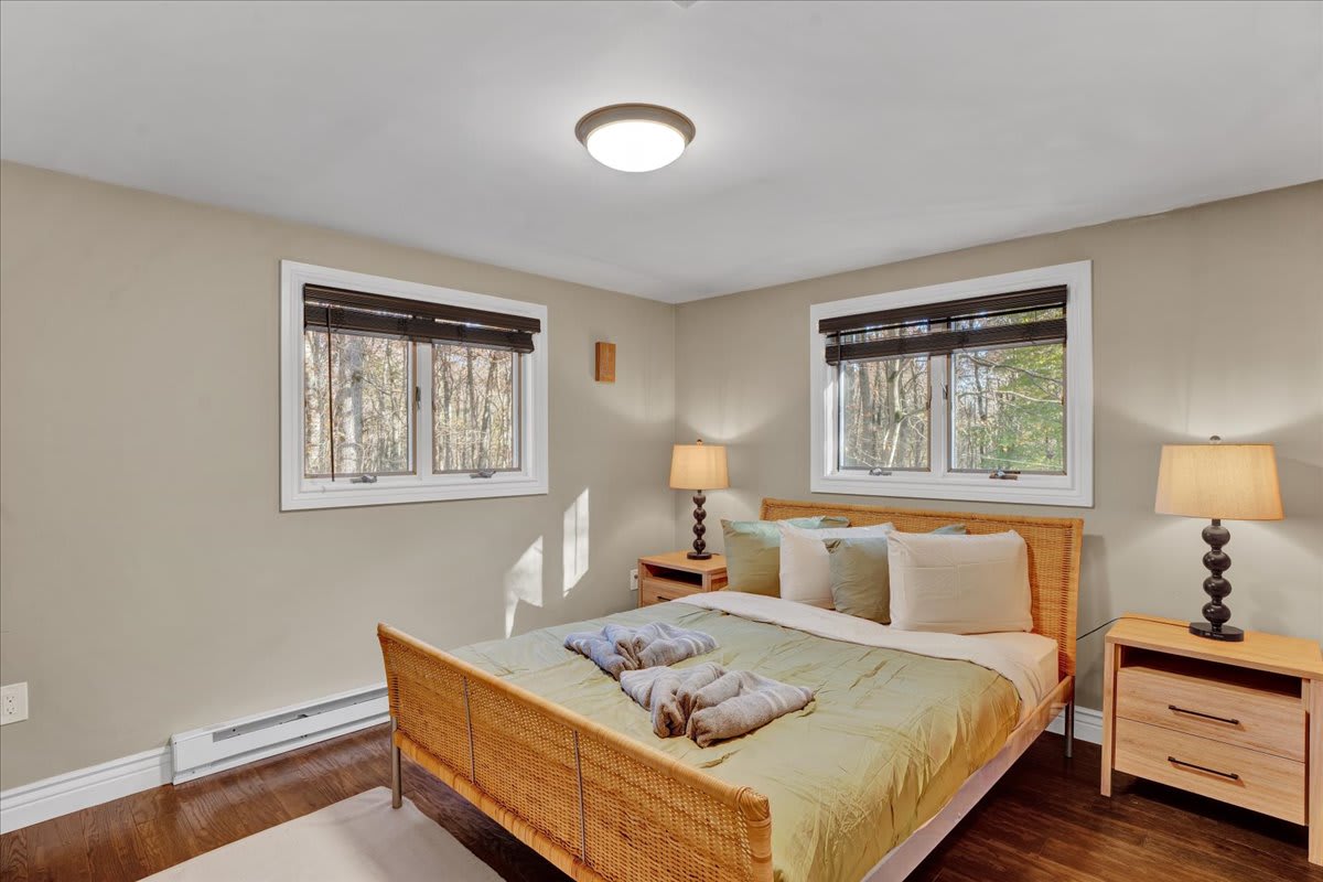 A beautifully designed space with a touch of warmth, this bedroom features a plush bed, charming nightstands, and calming natural light. A true retreat for a good night's sleep.