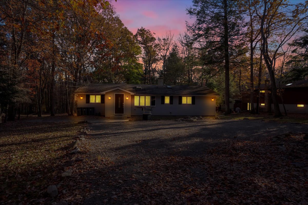 As dusk settles, the home glows warmly against the backdrop of the evening sky. A tranquil retreat surrounded by nature, offering the perfect balance of comfort and seclusion.