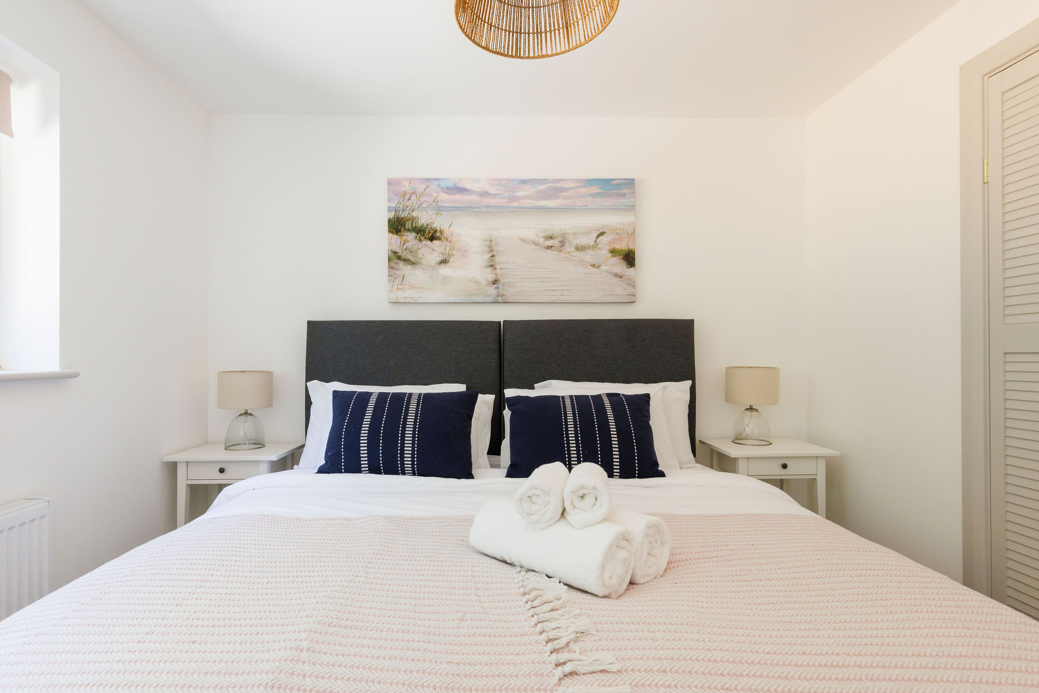 Relax in our serene bedroom with plush bedding and beach-inspired decor