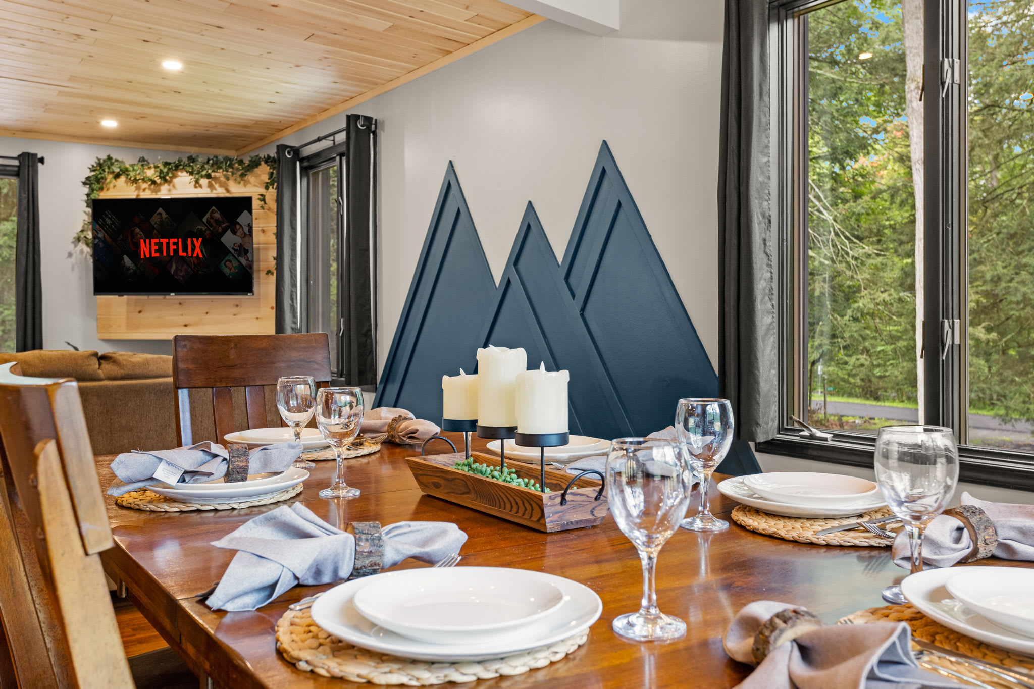 Elegant Cabin-Style Dining – A beautifully set dining table with rustic charm, warm lighting, and large windows offering scenic nature views.