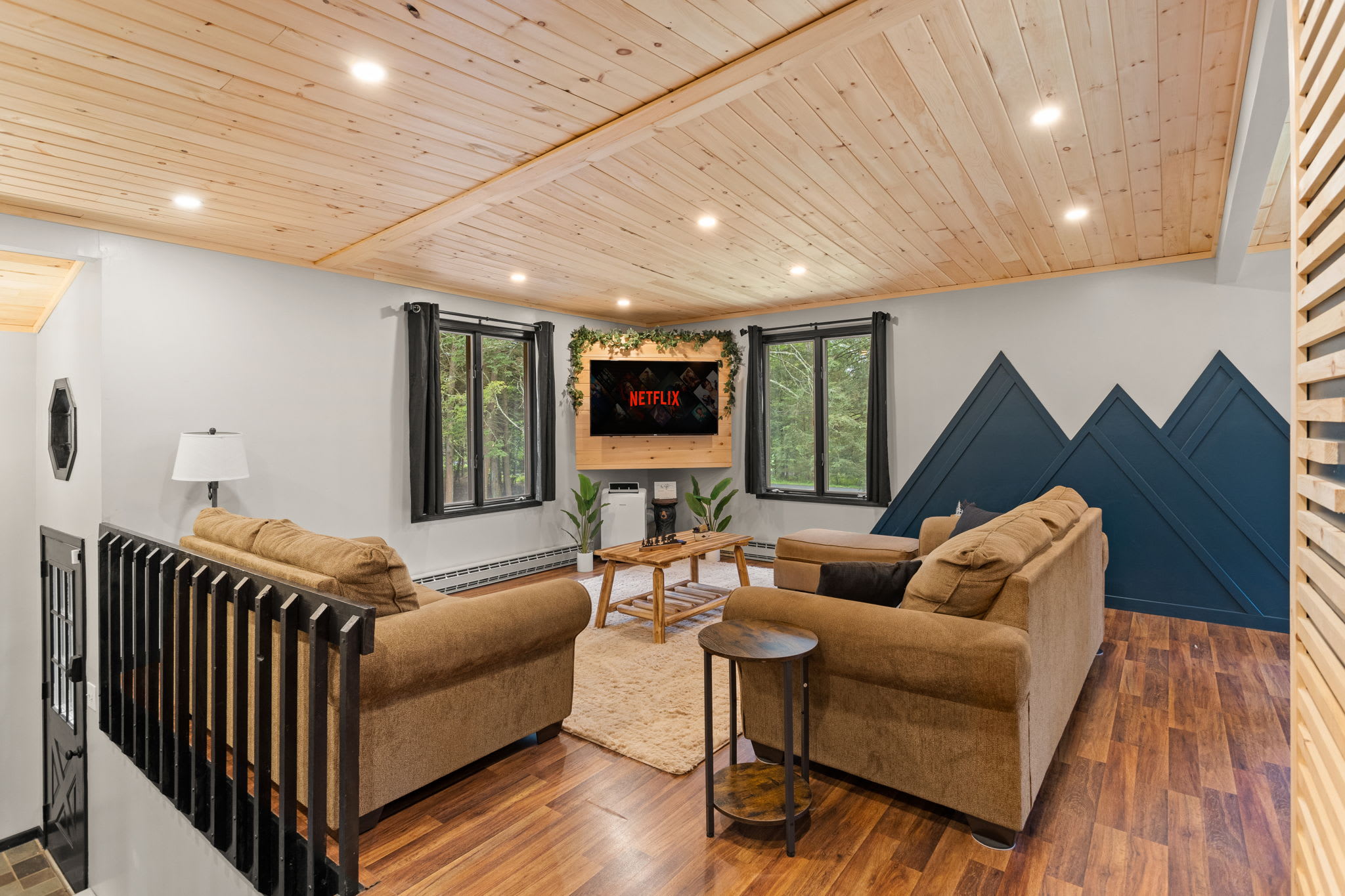 Bright & Airy Living Room – A stunning living space with warm wood ceilings, unique mountain-inspired wall art, and large windows that bring in natural light.