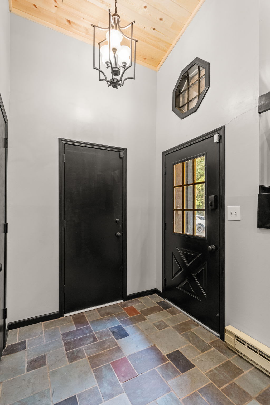 Warm & Welcoming Entryway – A charming entrance featuring elegant lighting, a modern black door, and rustic tile flooring for a stylish first impression.
