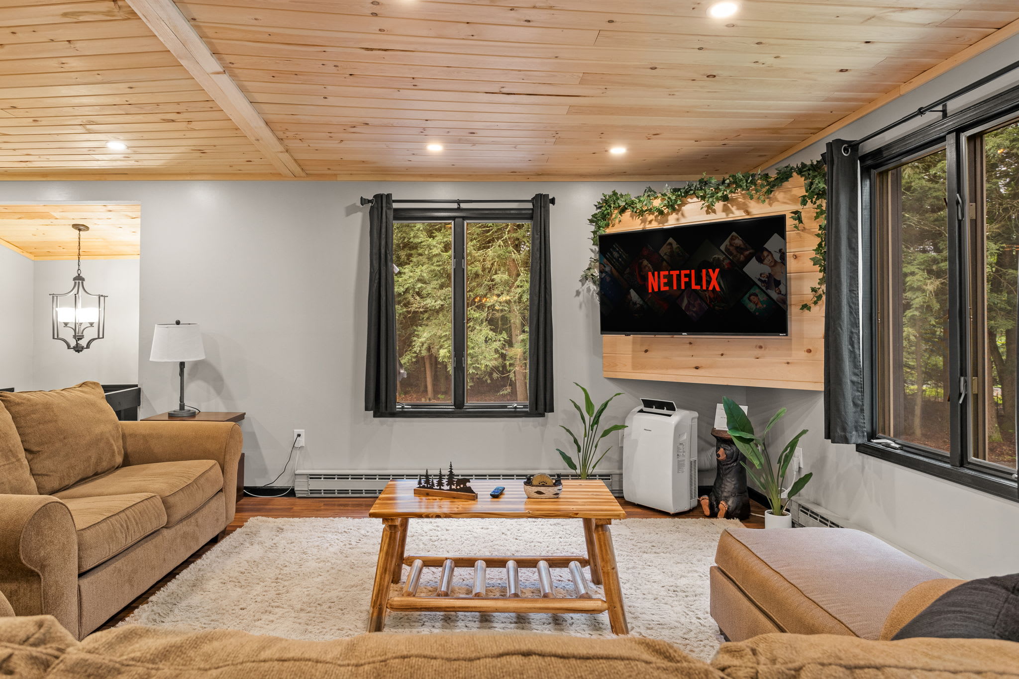 Warm & Inviting Living Space – A beautifully designed lounge with cozy seating, wood accents, and large windows that bring in natural light and forest views.