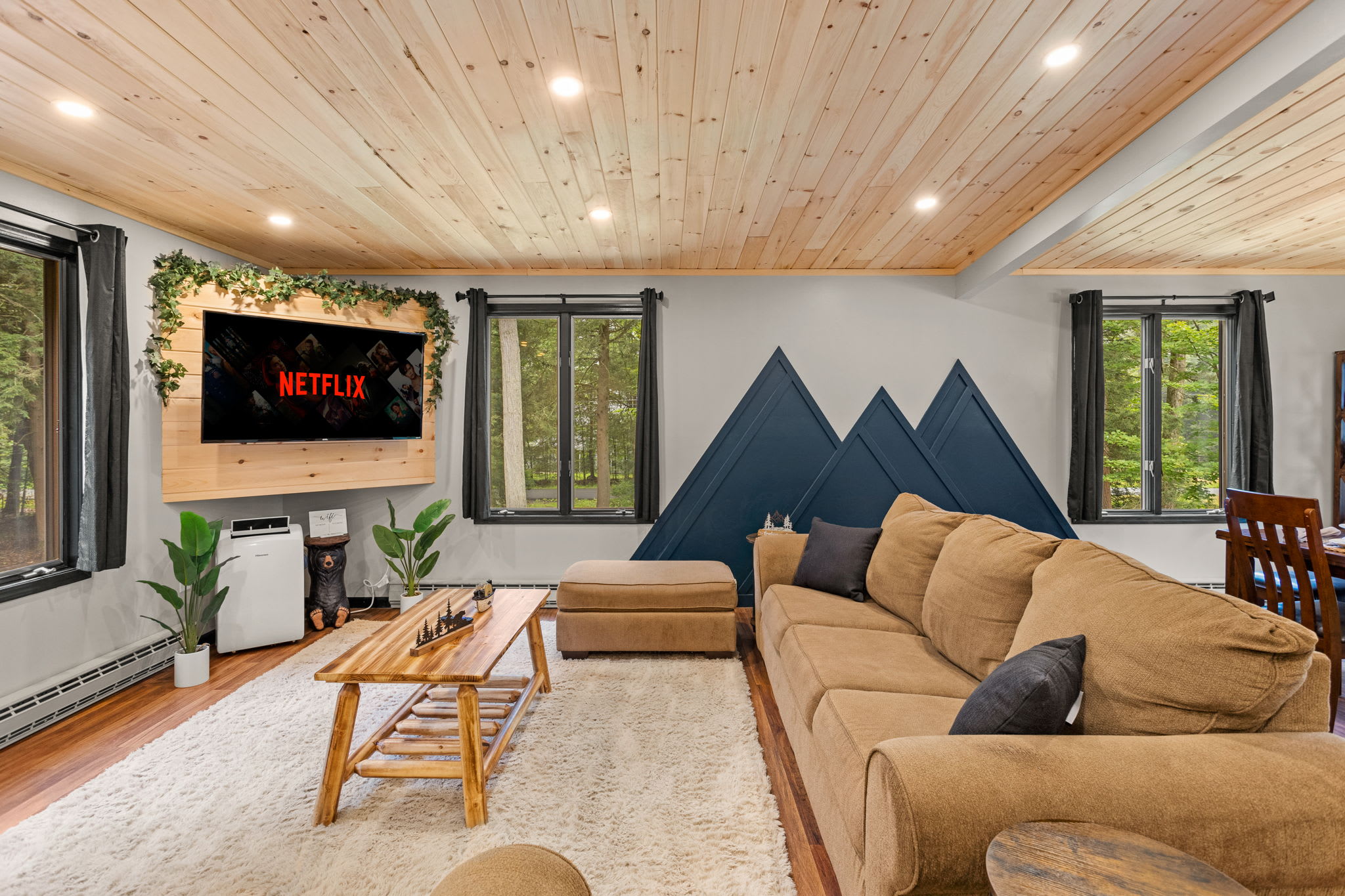 Cozy Living Room with a Mountain Vibe – A stylish and inviting lounge area featuring mountain-inspired wall art, warm wood ceilings, and a large sectional for ultimate relaxation.