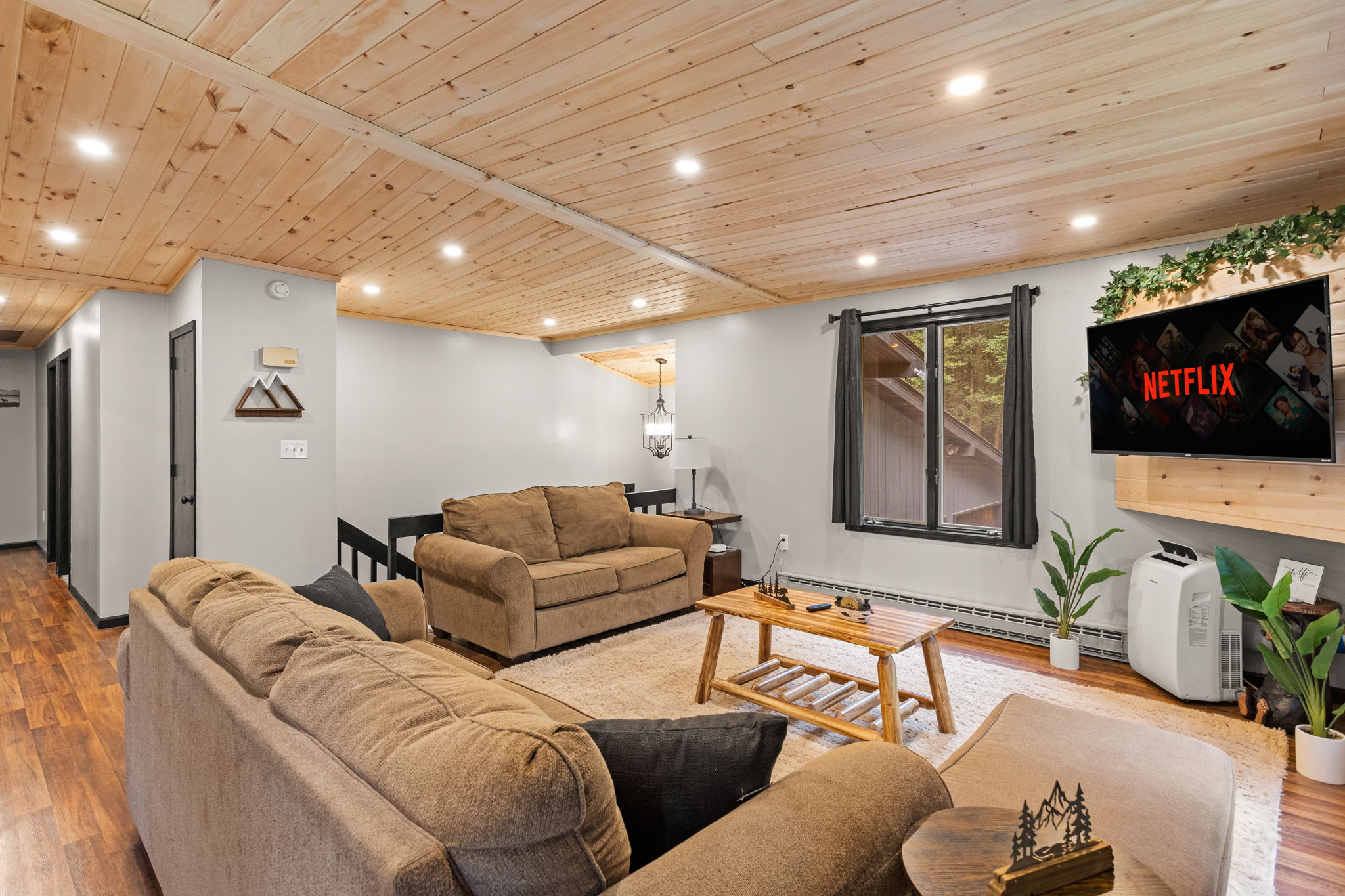 Spacious & Airy Lounge Area – A well-lit and open-concept living room with plush seating, warm wood ceilings, and a cozy atmosphere perfect for gathering.