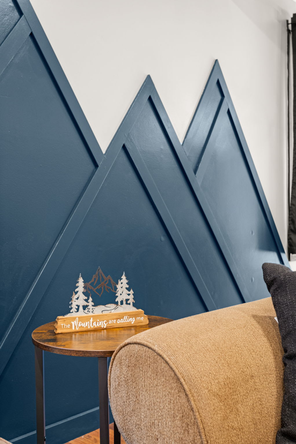 Bold & Unique Accent Wall – A striking blue geometric wall design that adds a modern and adventurous touch to the cozy living area.