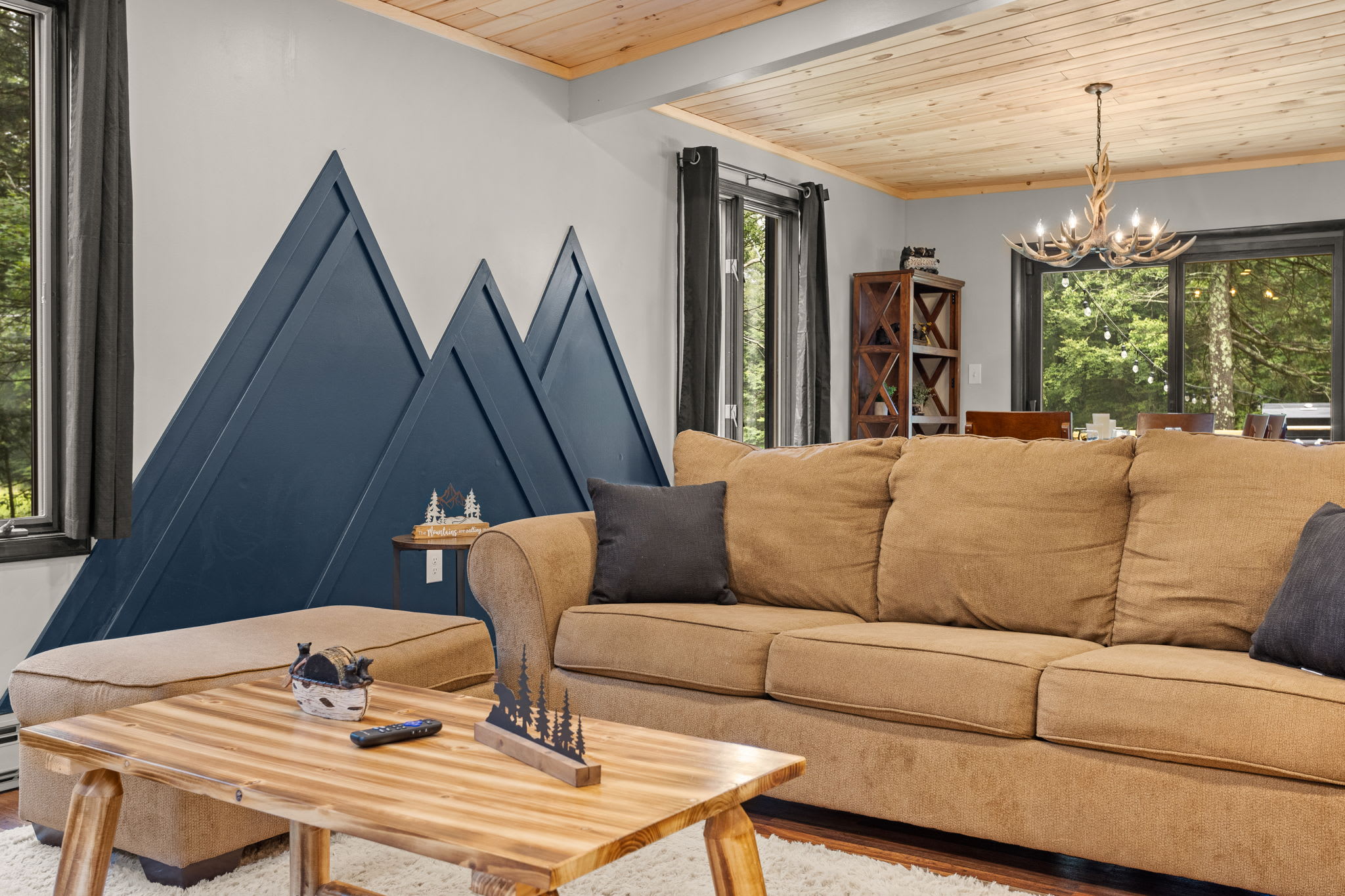 Modern Mountain-Inspired Living Room – A cozy lounge area featuring a unique mountain-themed accent wall, earthy tones, and warm wood finishes for a stylish and inviting space.