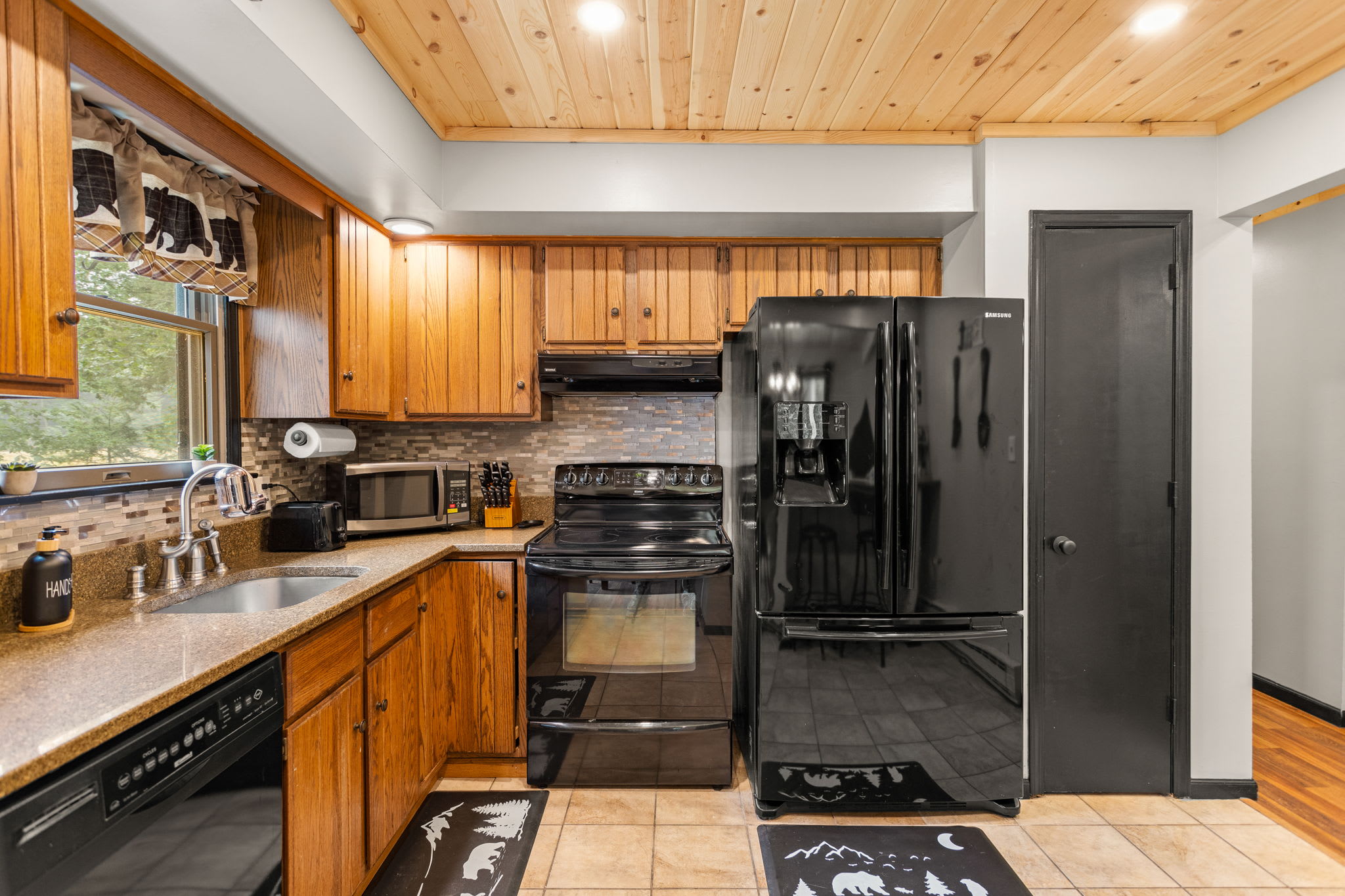 Rustic & Modern Kitchen Blend – A well-equipped kitchen featuring warm wooden cabinetry, sleek black appliances, and stylish backsplash tiles for a perfect mix of charm and function.