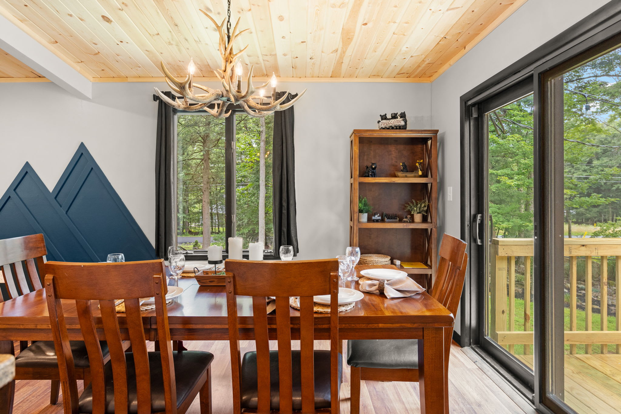 Dining with a View – A cozy dining area with a classic wooden table, elegant chandelier, and sliding glass doors leading to the outdoor deck, perfect for enjoying meals with a scenic backdrop.