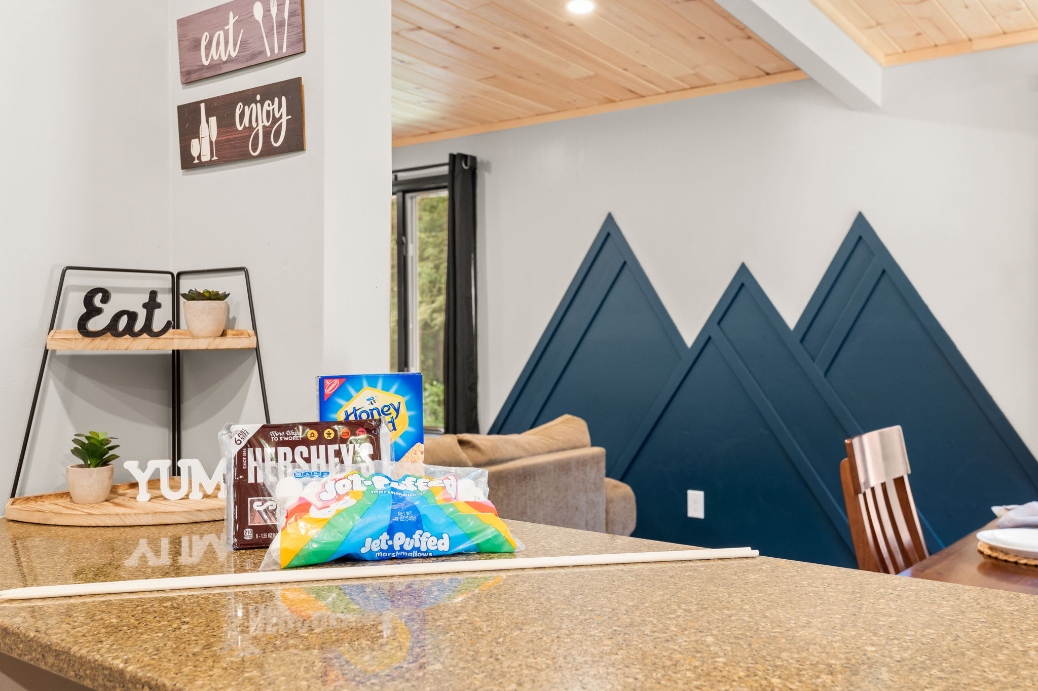 Rustic Kitchen Charm with a Modern Touch – A beautifully designed space with playful "Eat" decor, warm wooden accents, and a peek into the cozy living area.