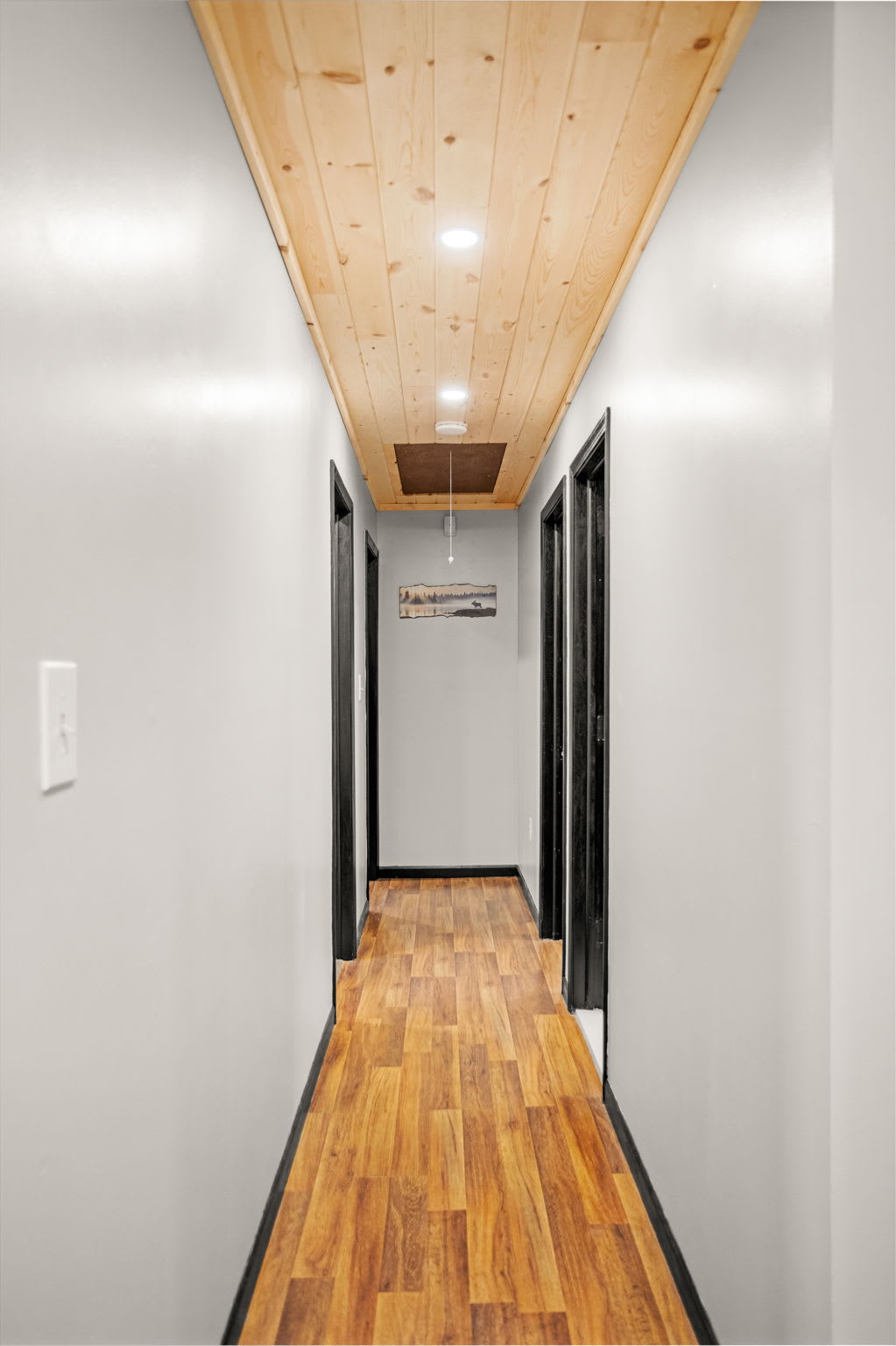 Sleek & Stylish Hallway – A bright and modern hallway with warm wood flooring and recessed lighting, leading to the inviting living and bedroom areas.