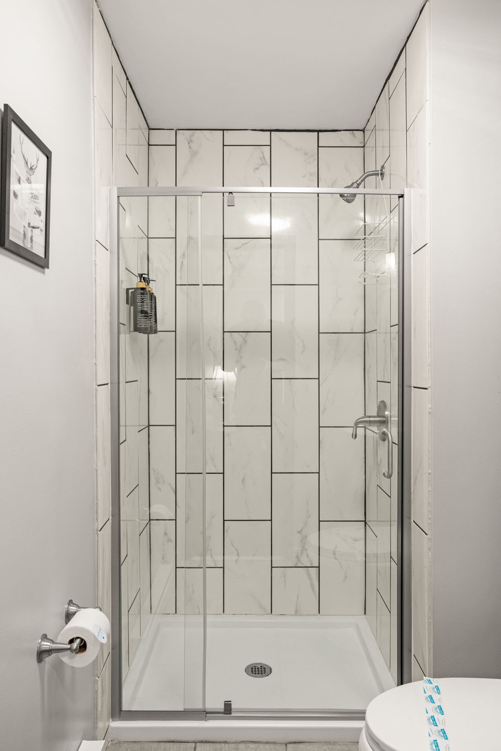 Bright & Elegant Walk-In Shower – A luxurious shower space with crisp white tiles and black hardware, blending modern and minimalist aesthetics.