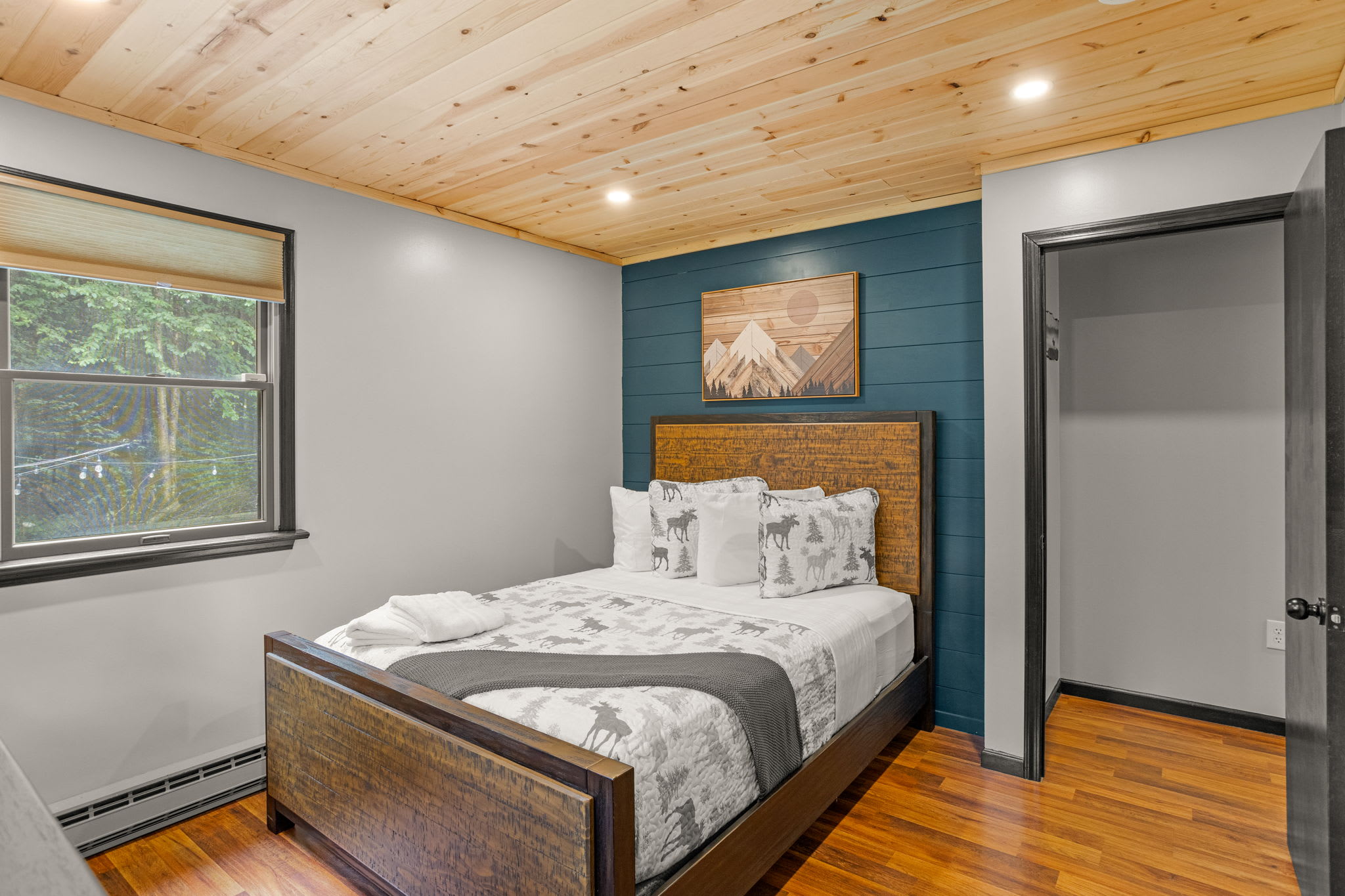 A cozy sleeping space with warm wooden ceilings, a comfortable bed, and thoughtful decor for a relaxing stay.