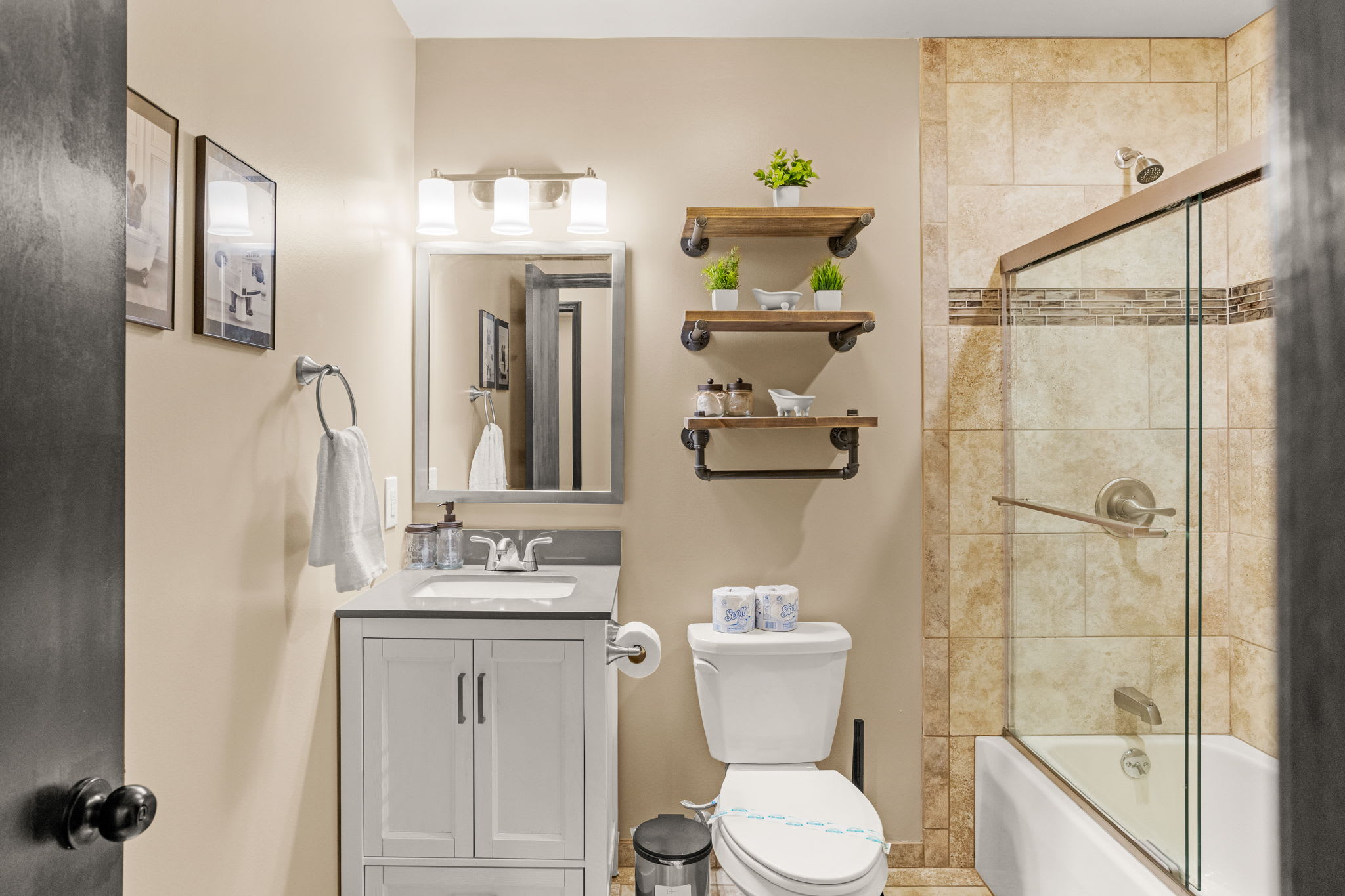 Spa-Like Bathroom Oasis – A beautifully designed bathroom featuring warm neutral tones, sleek glass shower doors, and floating shelves for added charm.