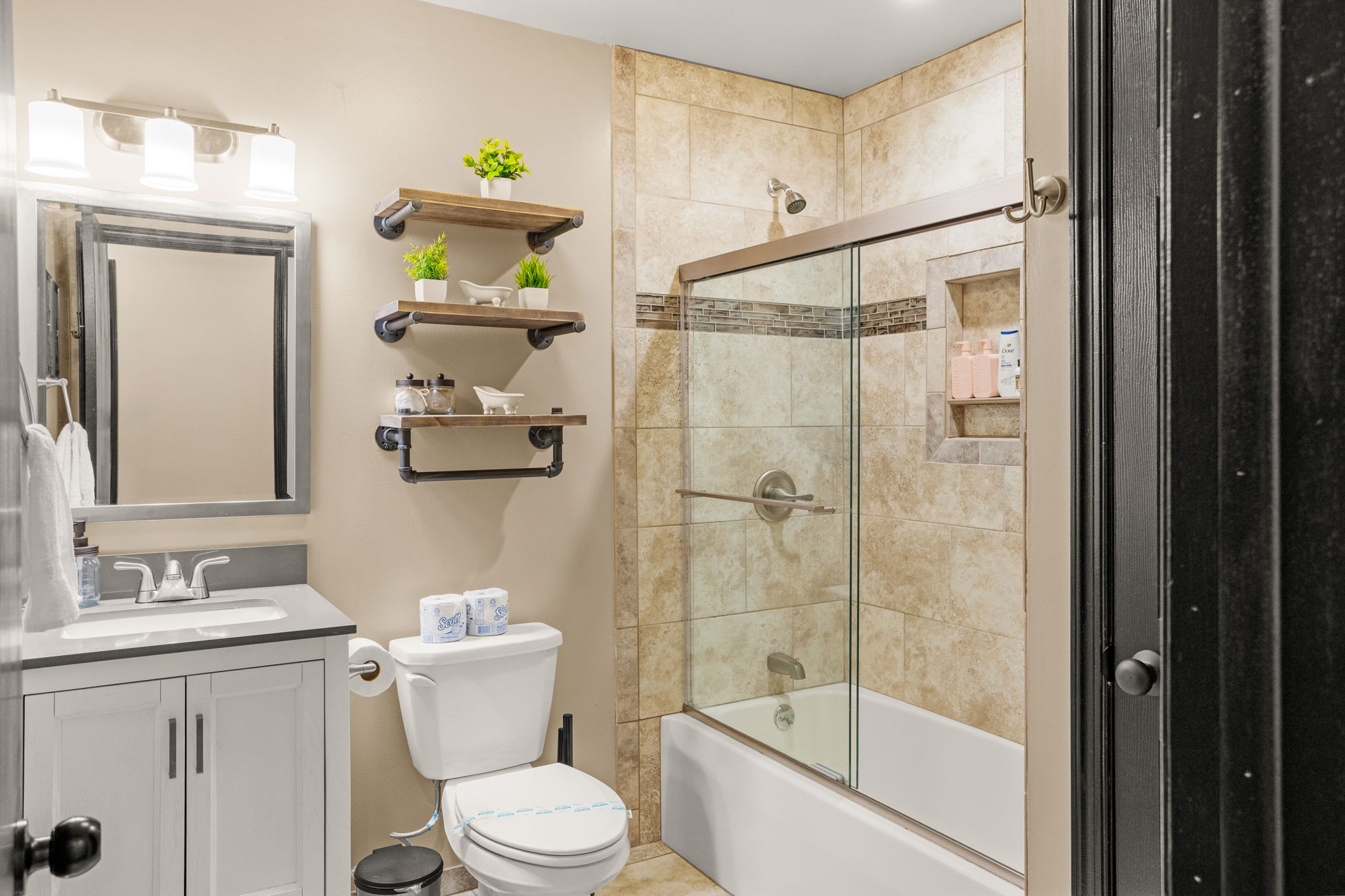 A beautifully designed space with neutral tones, a sleek vanity, and a glass-enclosed bathtub for a spa-like experience.