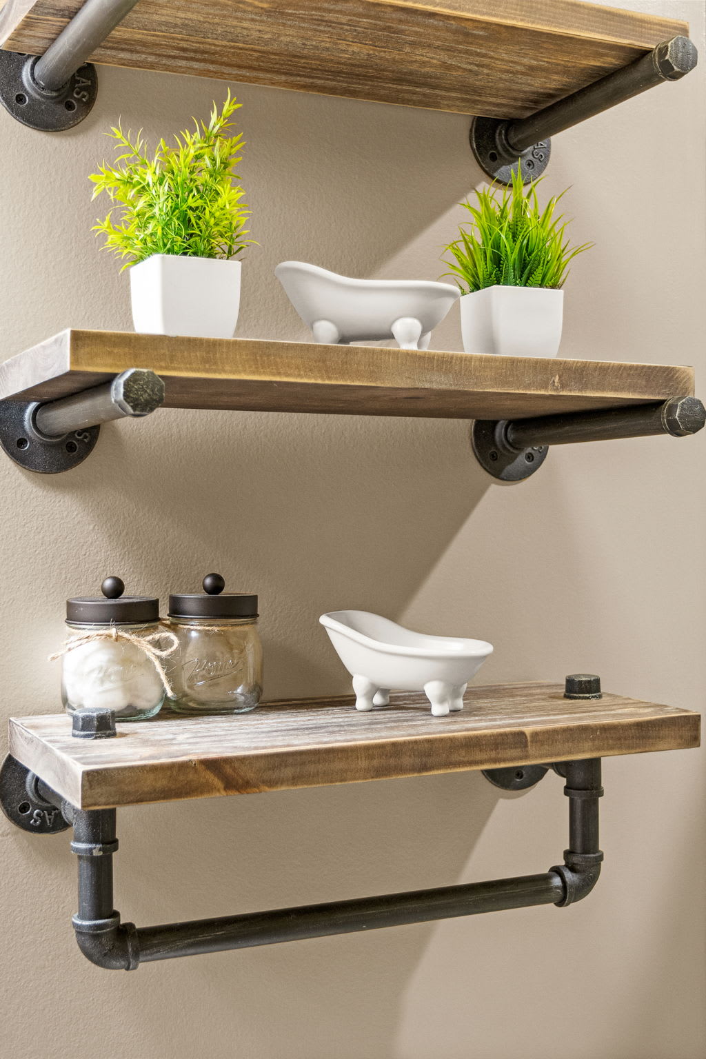 Stylish floating wooden shelves with industrial pipe brackets provide both charm and functionality for bathroom essentials.