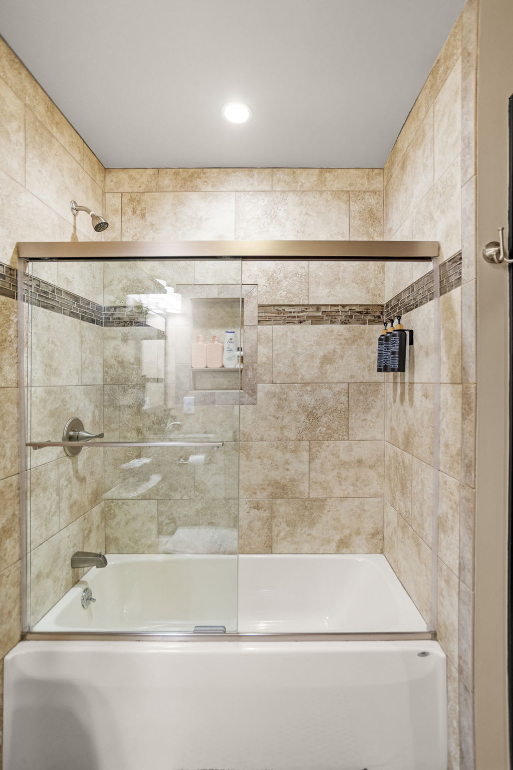 A stunning shower space with warm tile textures, a sleek glass door, and elegant detailing for a high-end feel.