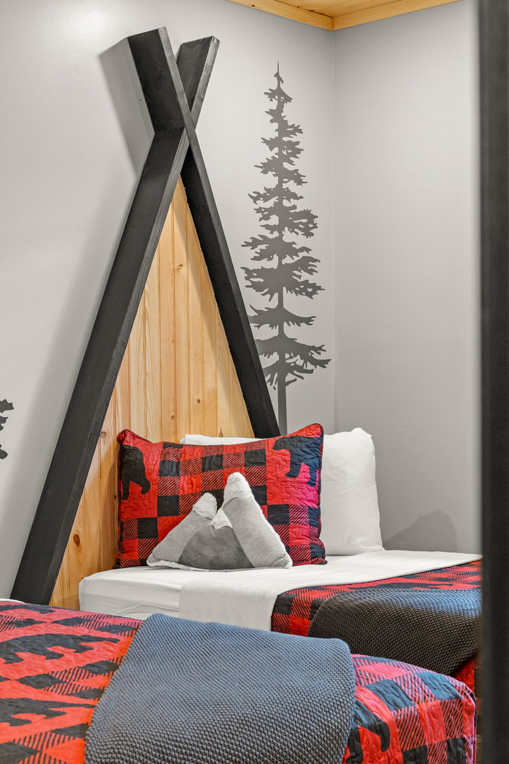 A close-up of the unique bed setup, featuring teepee-style wooden frames and cozy plaid bedding for a charming mountain retreat.