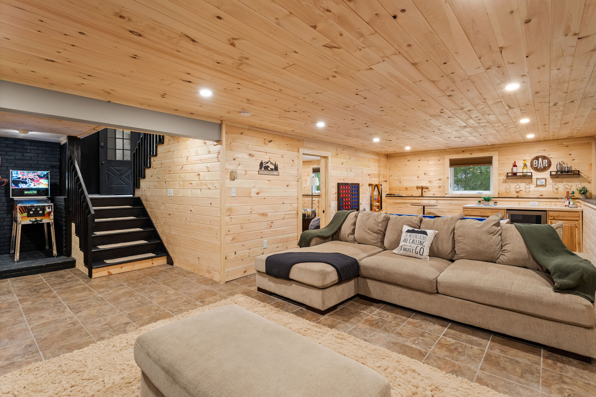 Expansive & Cozy Basement Lounge – A spacious entertainment area with plush sectional seating, warm wood walls, and an inviting atmosphere for relaxing or socializing.