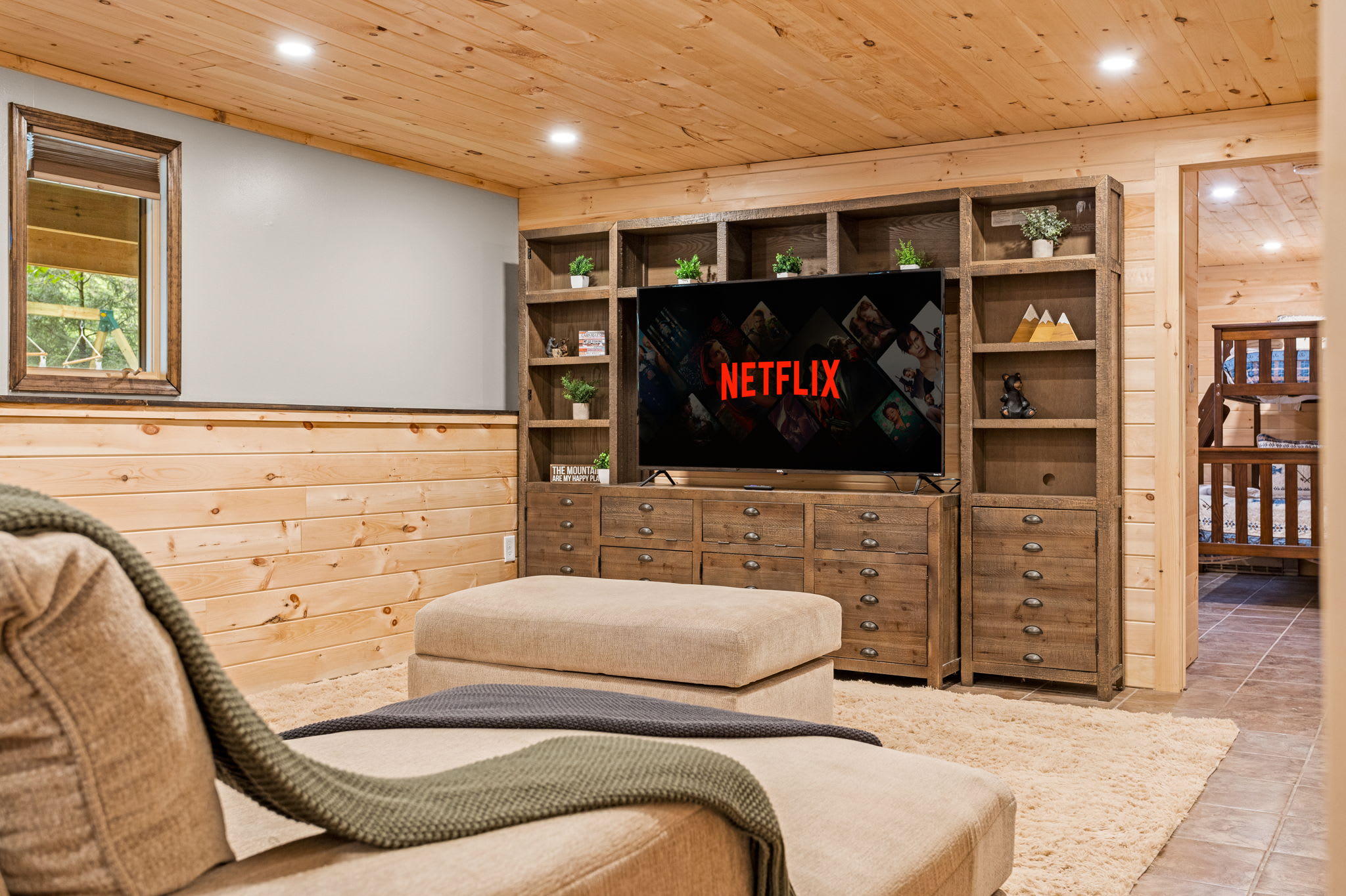  A cozy basement retreat featuring warm wood paneling, a built-in entertainment center, and plush seating for the perfect movie night.